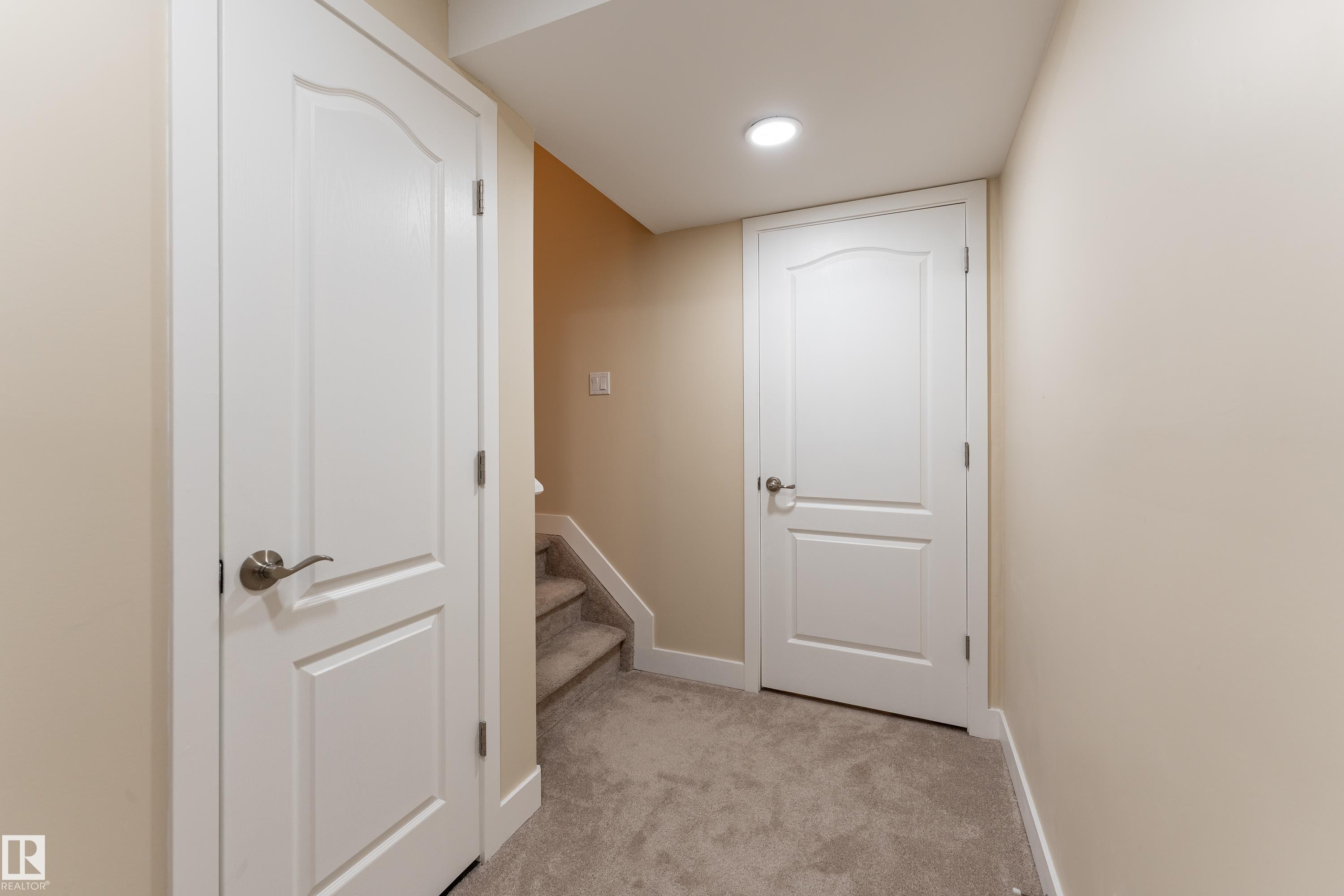 Carpeted hallway featuring a recessed ceiling light, two paneled doors with brushed nickel hardware, and neutral wall paint - 191 Reed Place, Leduc, AB - Indoor Photo Showing Other Room