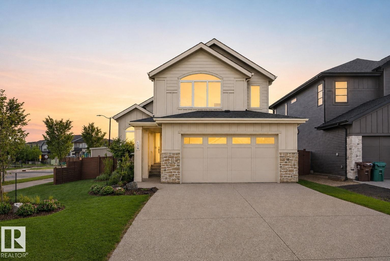Two-story residence featuring a two-car garage, stone accents, arched window, and a concrete driveway - 14 Jane Point(E), St. Albert, AB