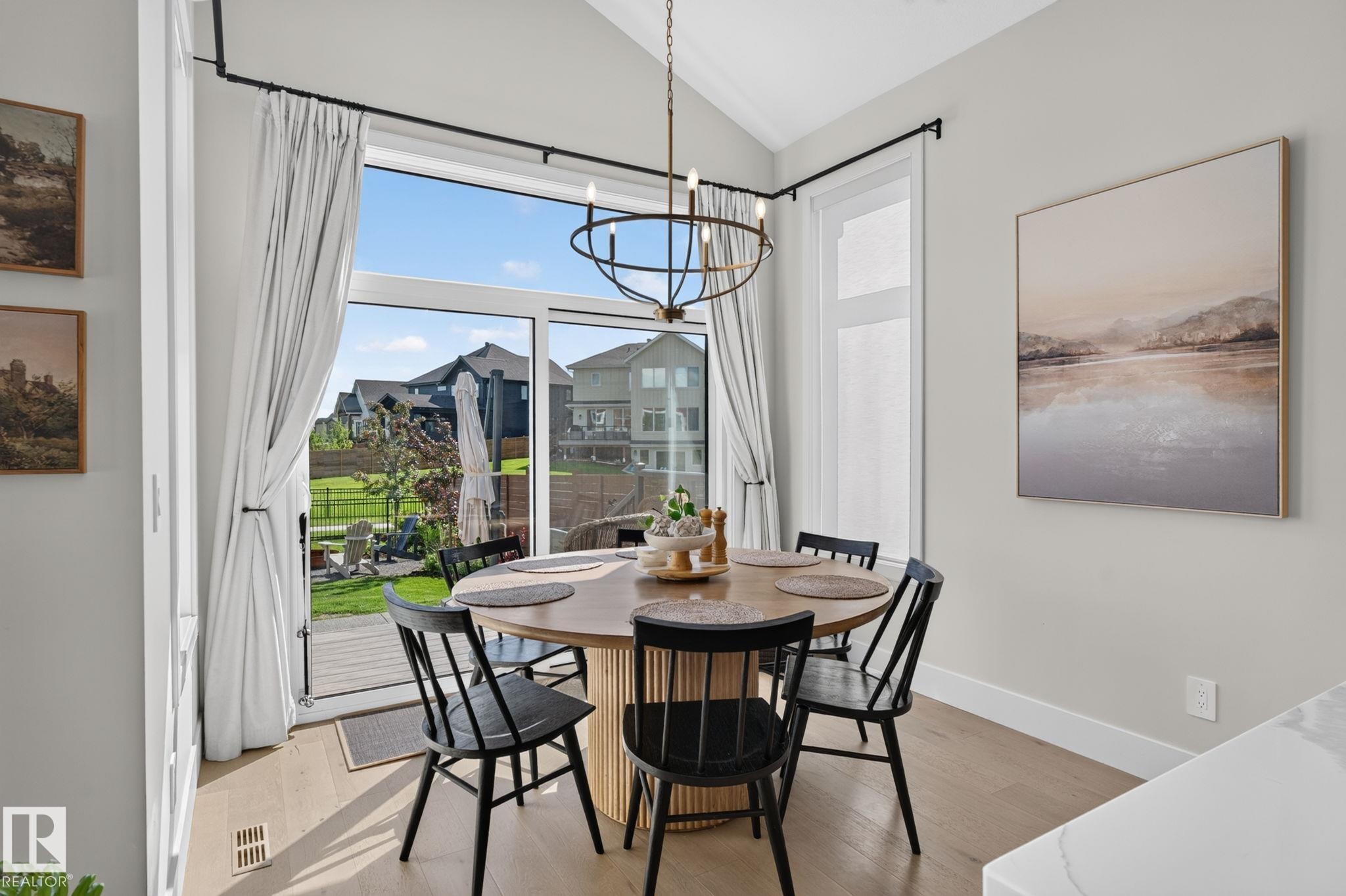 Dining area featuring wood-finish flooring, a circular wood table, and a contemporary chandelier - 14 Jane Point(E), St. Albert, AB