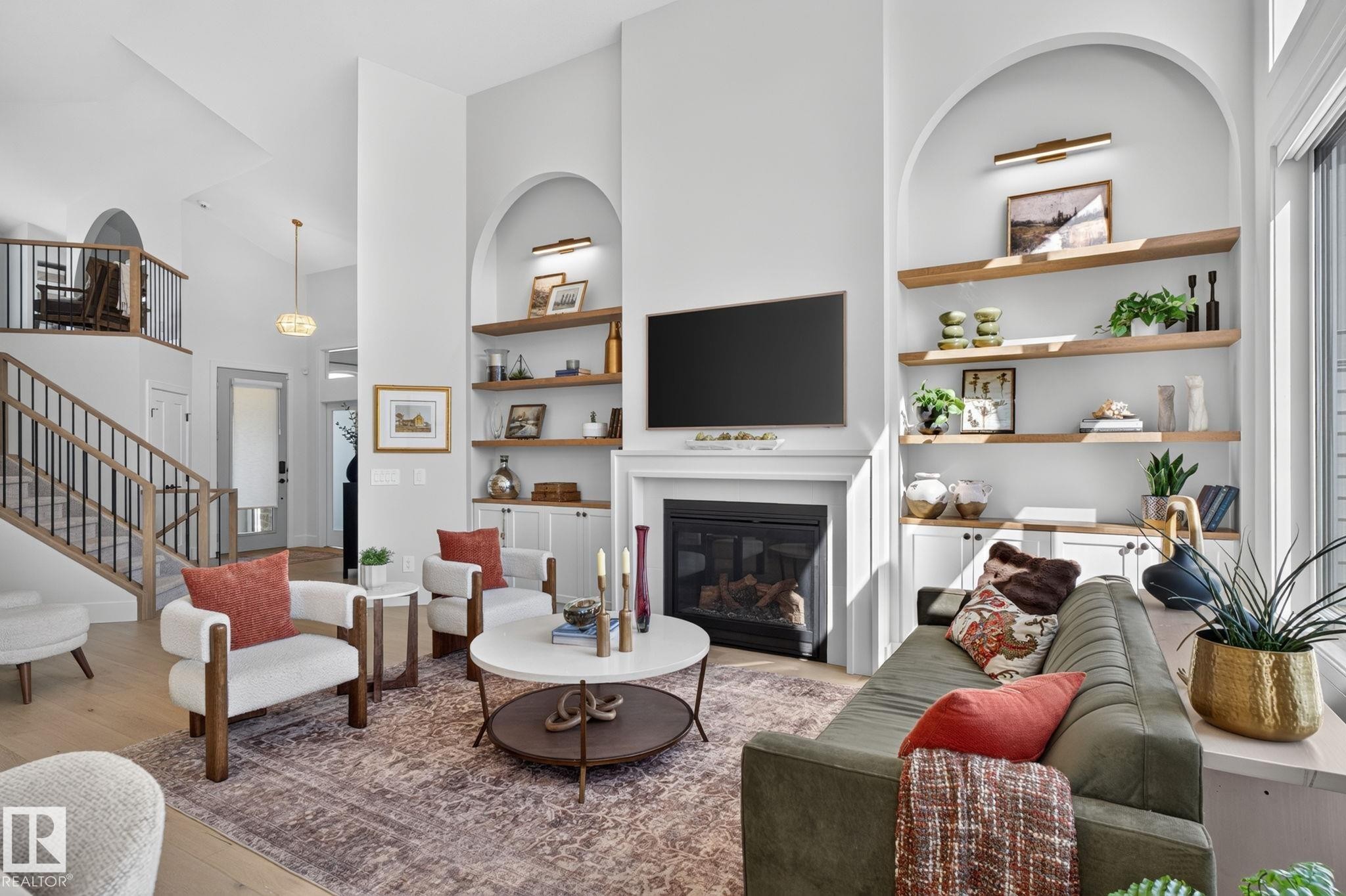 Living room featuring a fireplace with a white mantel, built-in shelving, high ceilings, and wood-finish flooring - 14 Jane Point(E), St. Albert, AB