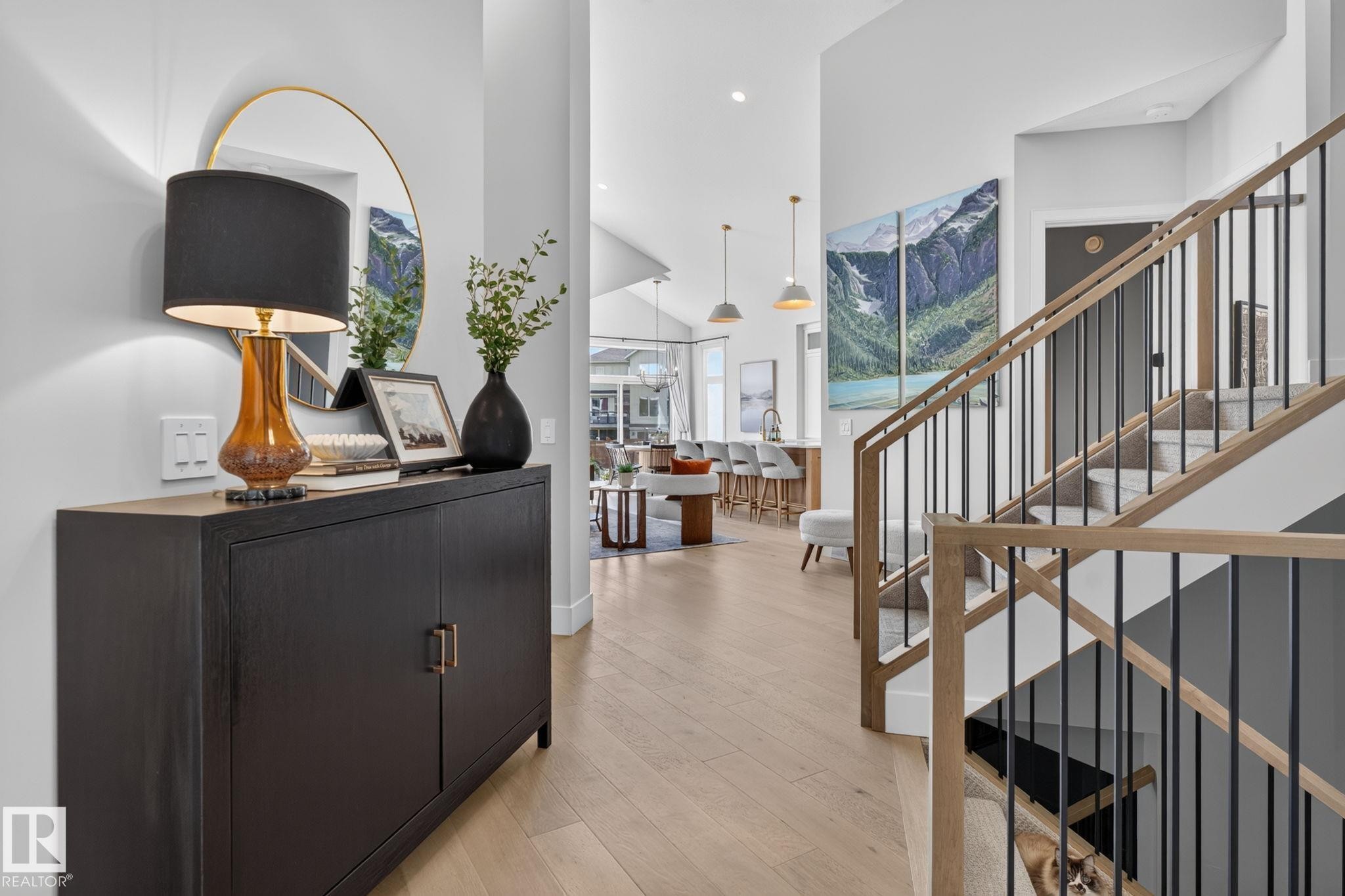 Entryway featuring light wood-finish flooring, a contemporary staircase with wood handrails and black balusters, and recessed lighting - 14 Jane Point(E), St. Albert, AB