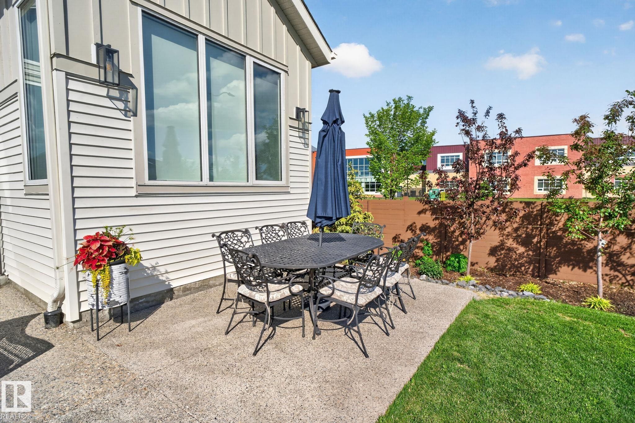 Private concrete patio featuring a manicured lawn and mature trees - 14 Jane Point(E), St. Albert, AB
