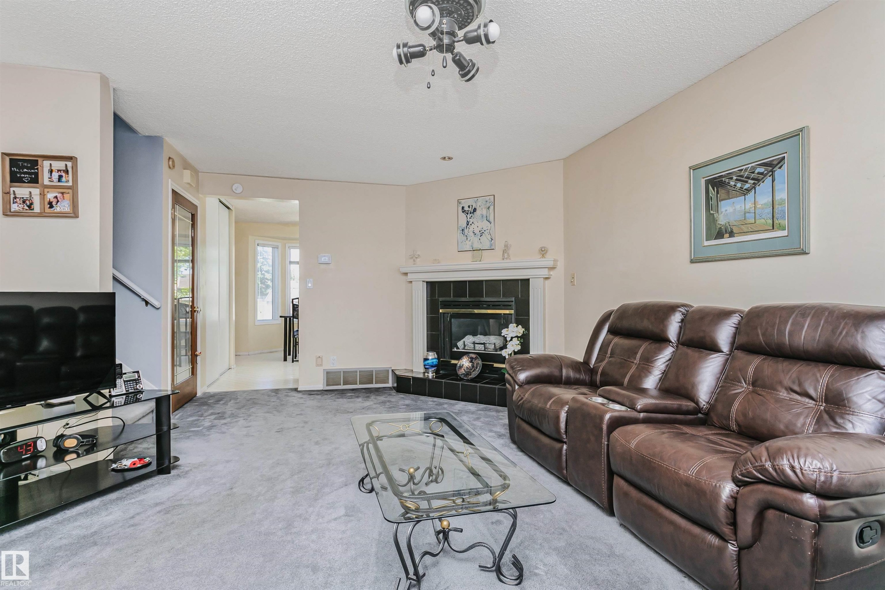 Living area featuring a corner fireplace with a white mantel and black tile surround - 1612 80A Street, Edmonton, AB