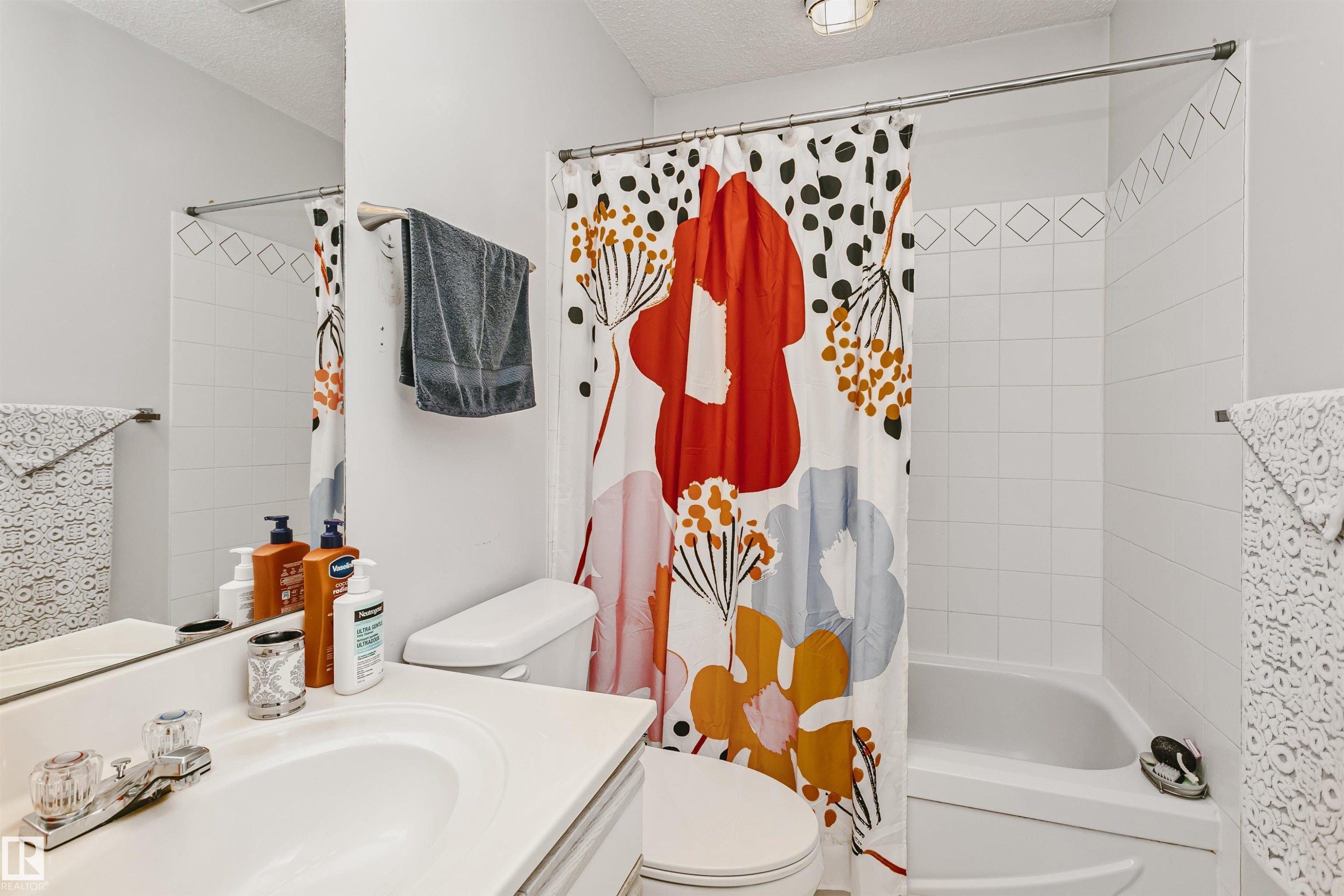 Bathroom featuring a white vanity with an integrated sink, a two-handle chrome faucet, and a toilet - 1612 80A Street, Edmonton, AB