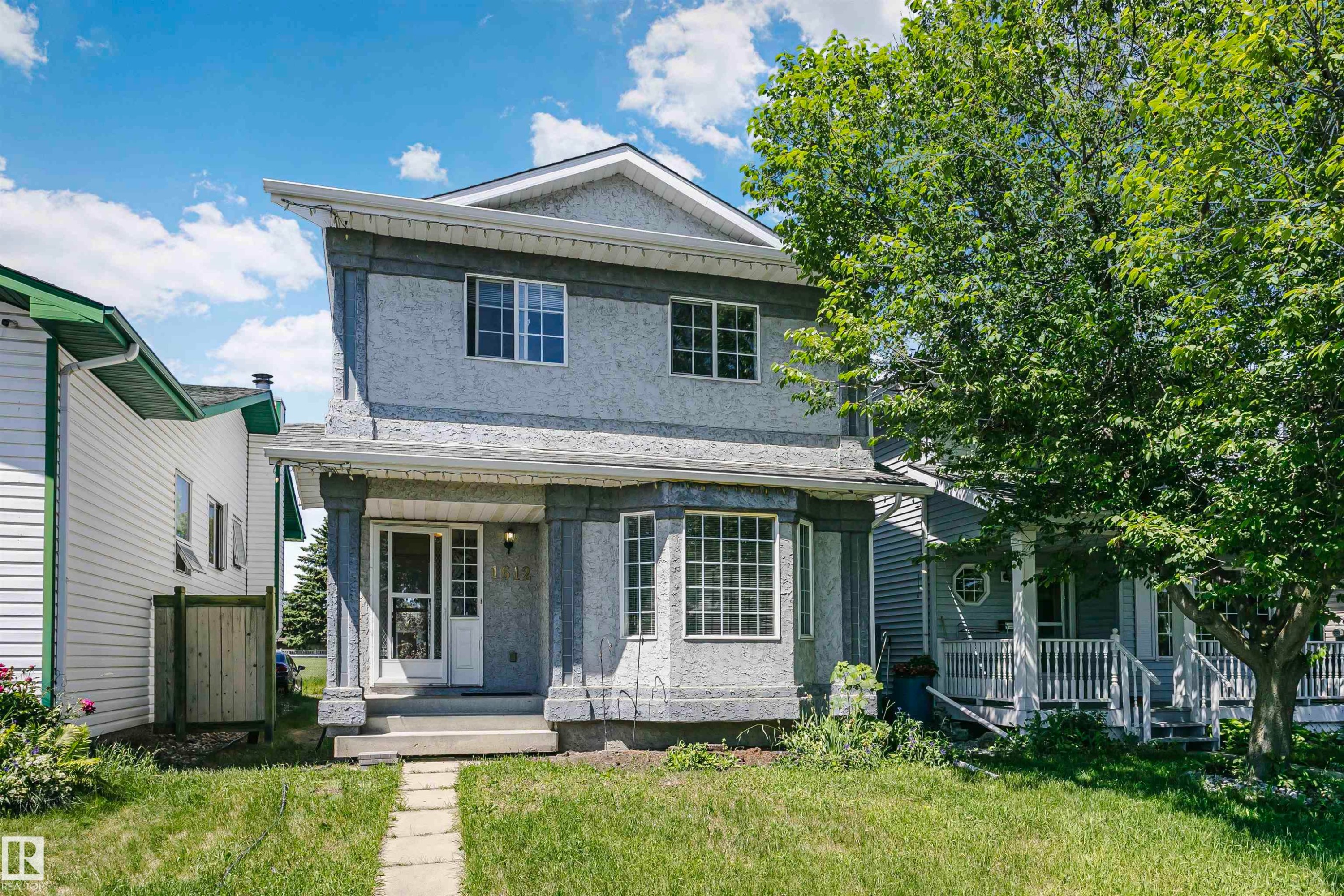 Stucco exterior with a covered porch featuring decorative columns - 1612 80A Street, Edmonton, AB