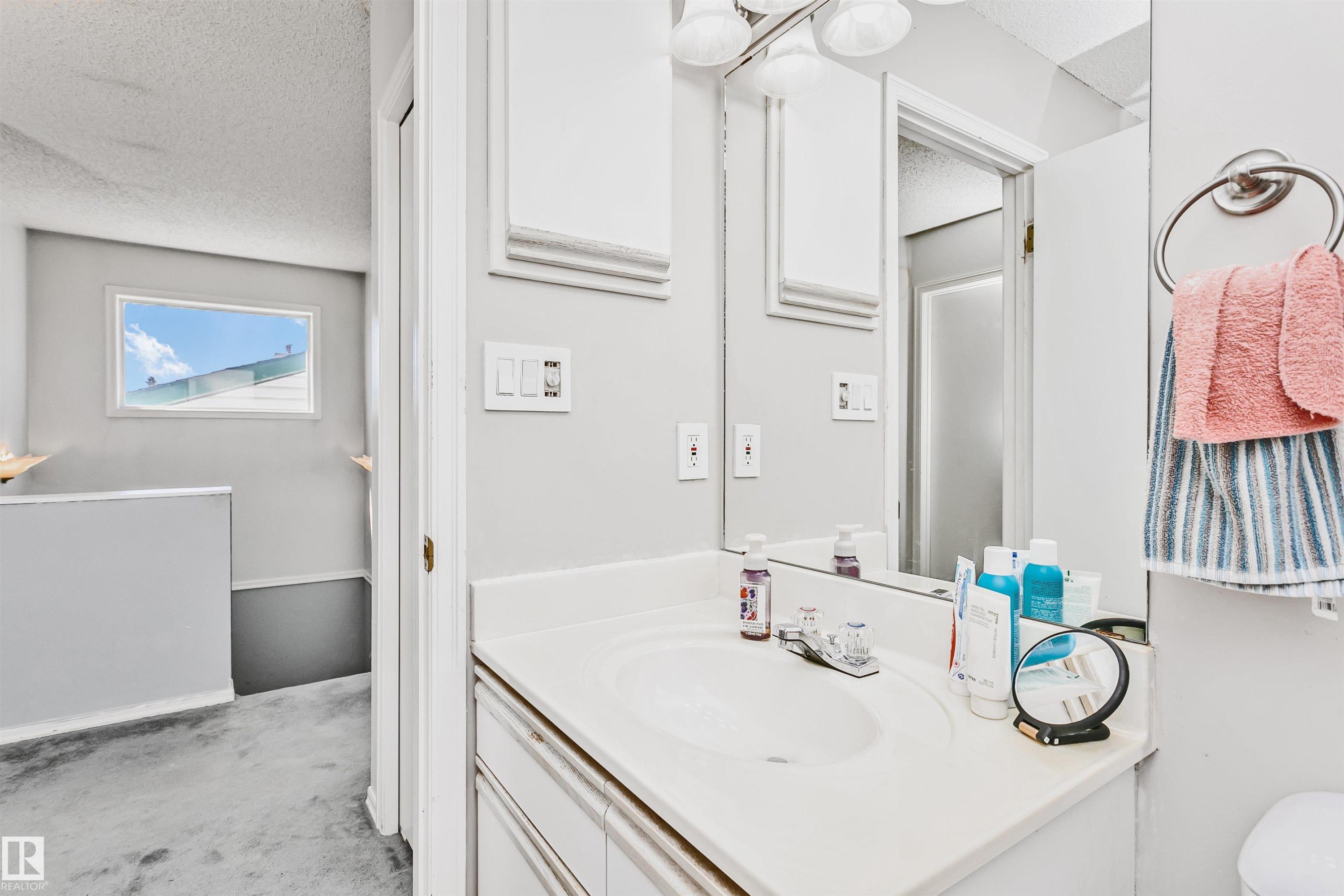 Bathroom vanity with an integrated sink, polished chrome faucet, and a large wall-mounted mirror - 1612 80A Street, Edmonton, AB