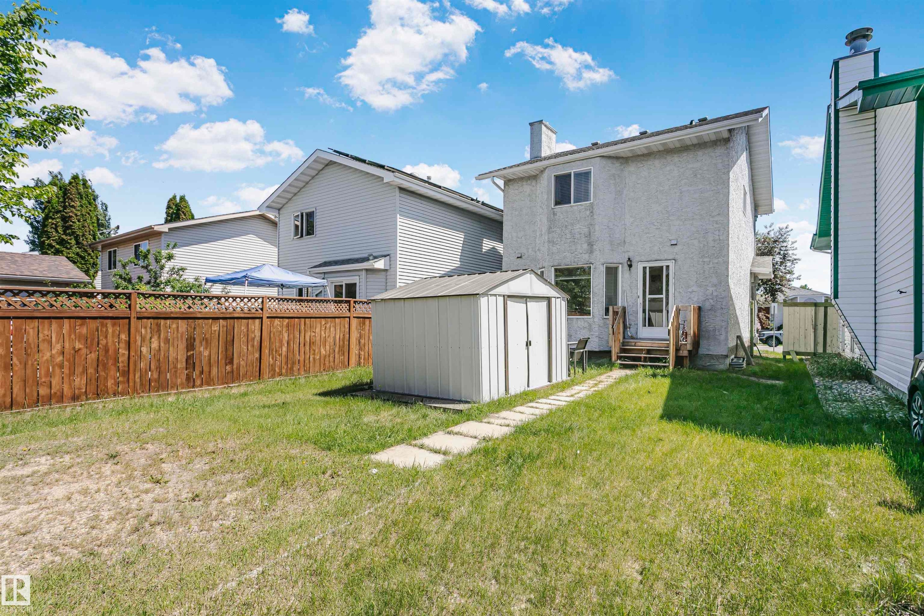 Backyard featuring a stucco exterior, a wood privacy fence with lattice top, a metal shed, a wood staircase, and a concrete paver path - 1612 80A Street, Edmonton, AB