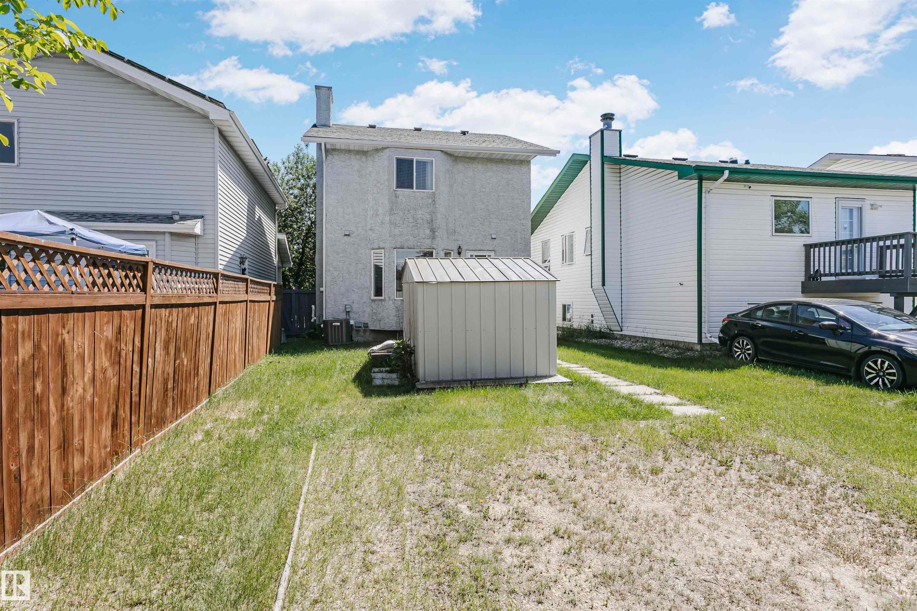 Expansive backyard featuring a wood fence with lattice top, a detached storage shed, and a stone paver pathway - 1612 80A Street, Edmonton, AB
