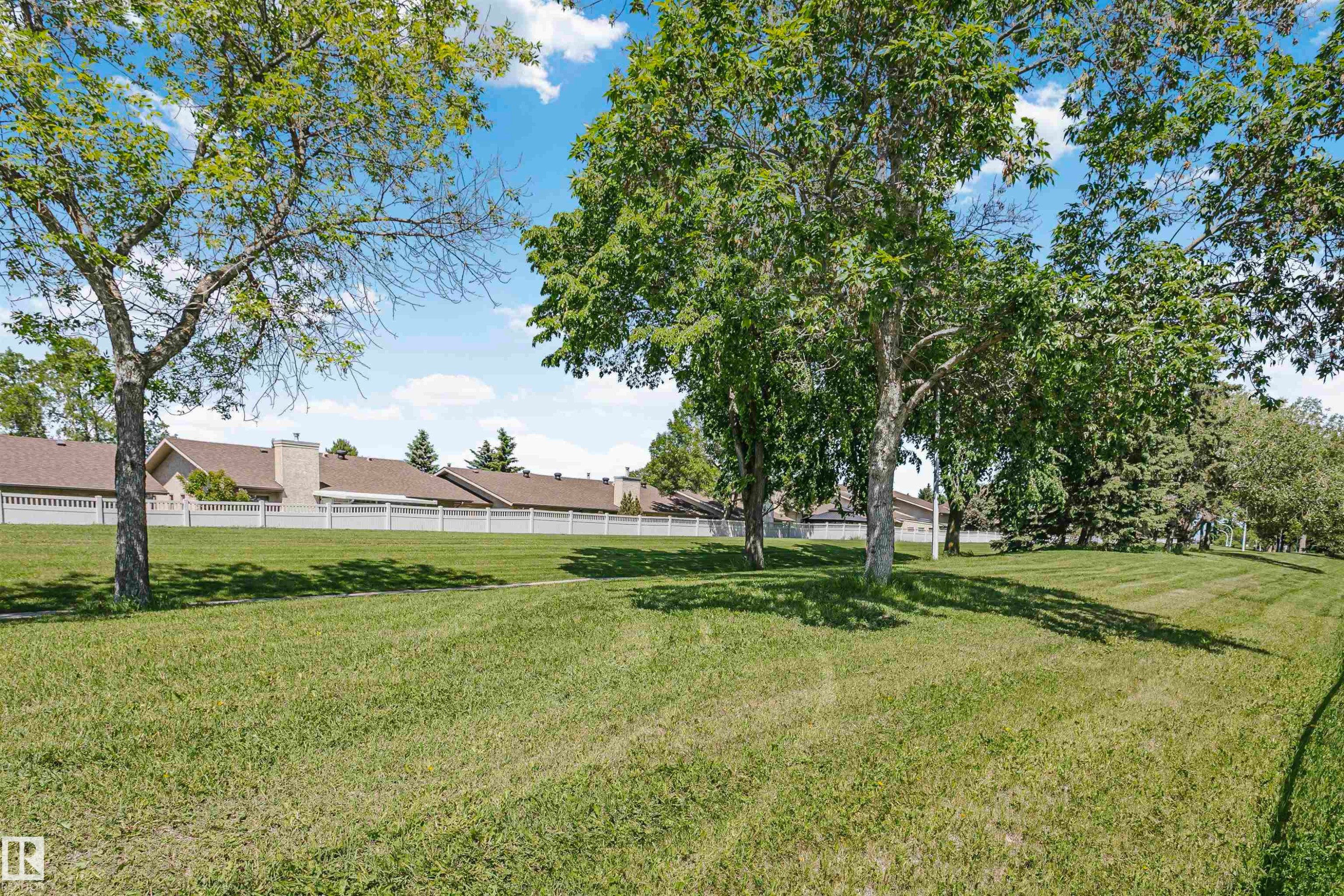 Expansive green space featuring mature trees and a white privacy fence - 1612 80A Street, Edmonton, AB