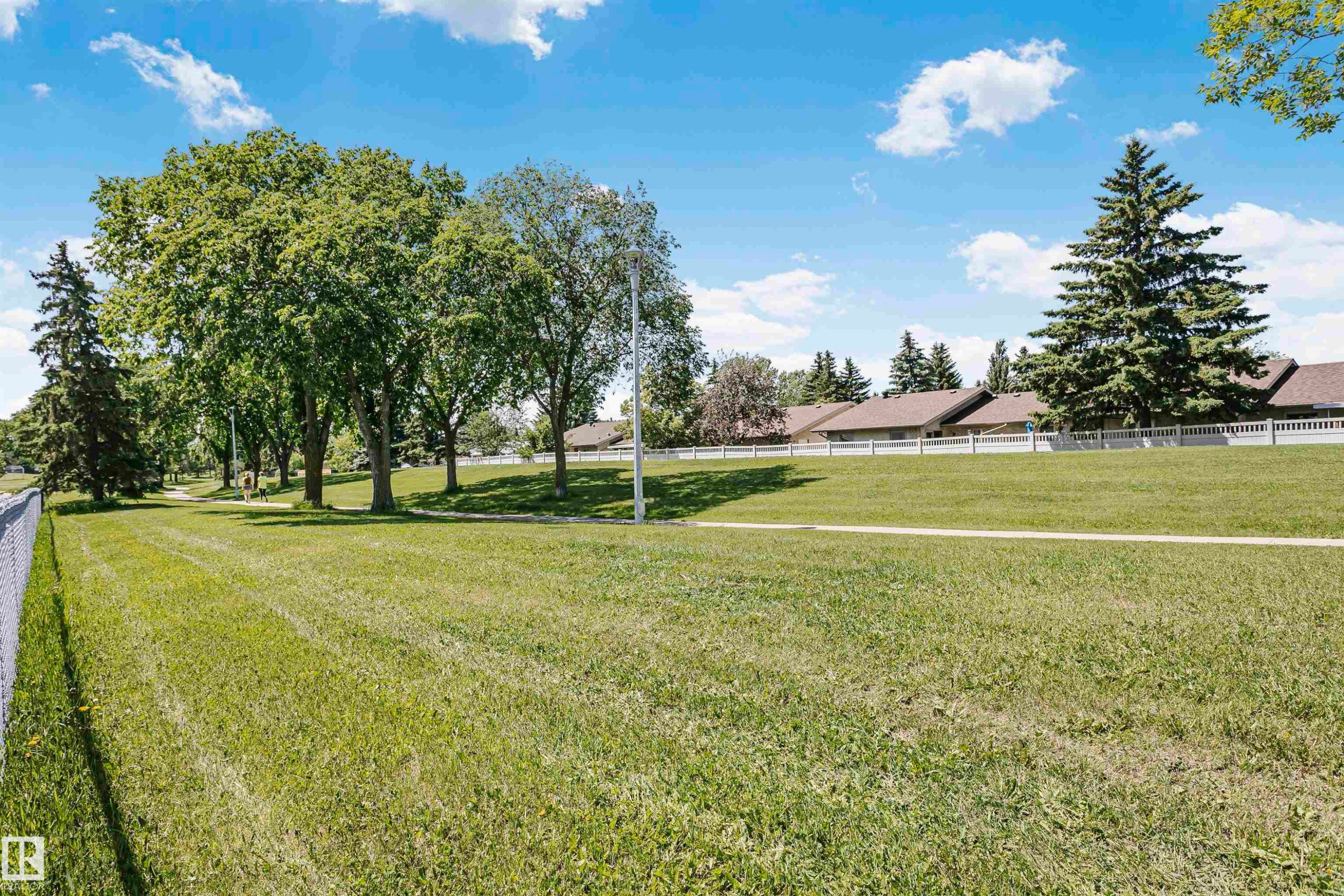 Expansive green space featuring a manicured lawn, mature deciduous trees, and evergreen trees - 1612 80A Street, Edmonton, AB