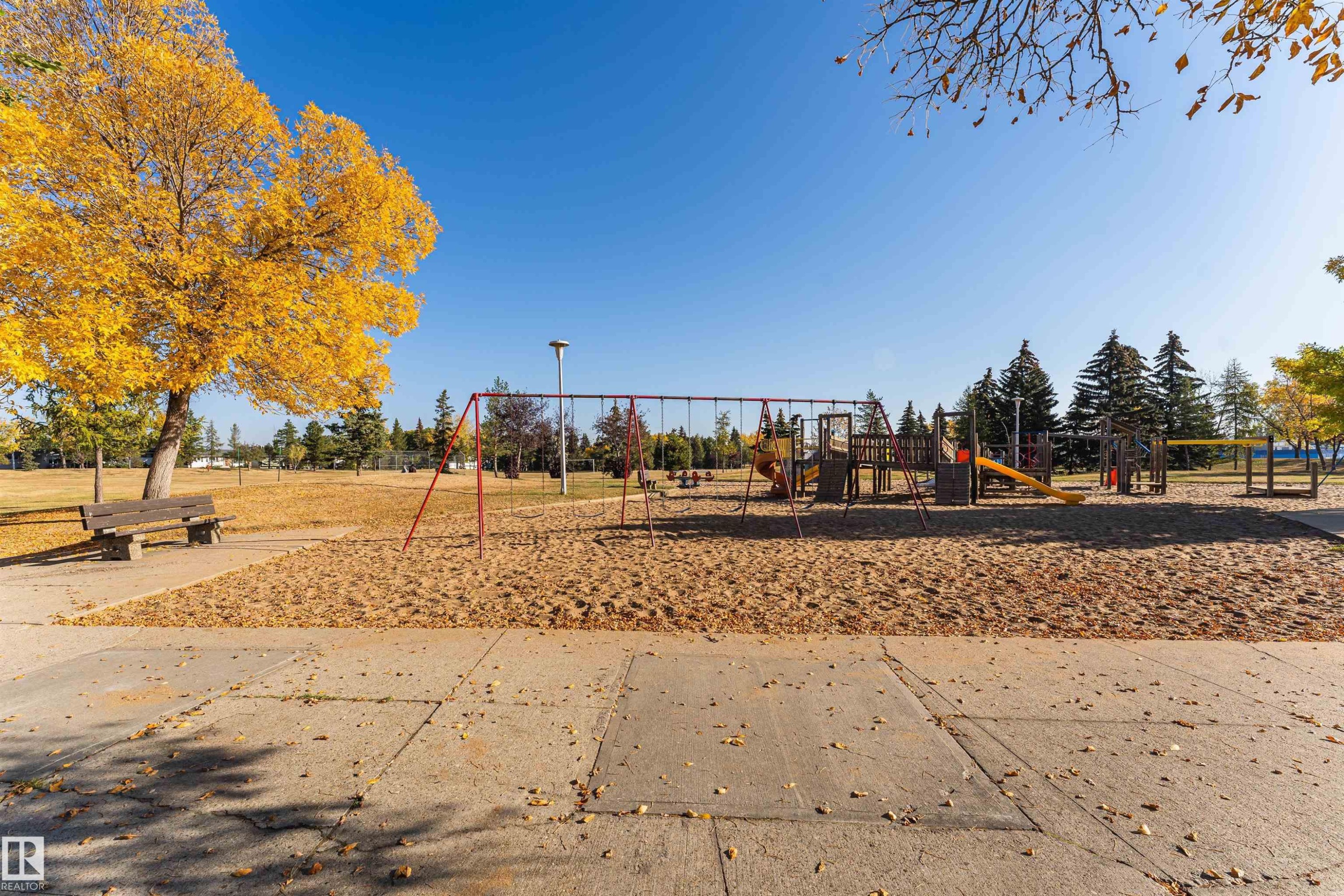 Expansive park grounds featuring a sand-based playground area, swing sets, climbing structures, and slides - 1612 80A Street, Edmonton, AB