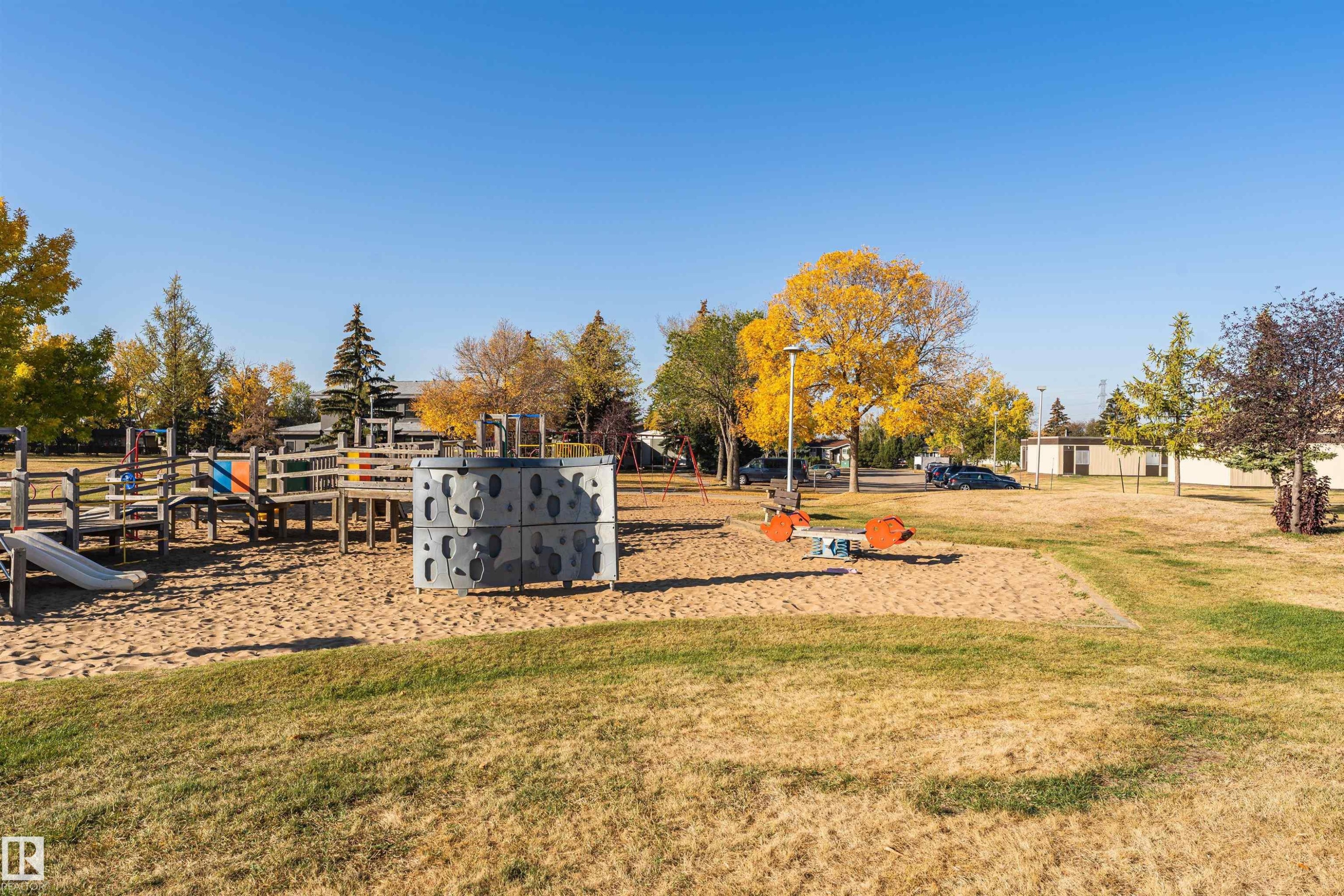 Outdoor recreation area featuring a sand-based playground with a slide, climbing structure, and teeter-totter - 1612 80A Street, Edmonton, AB