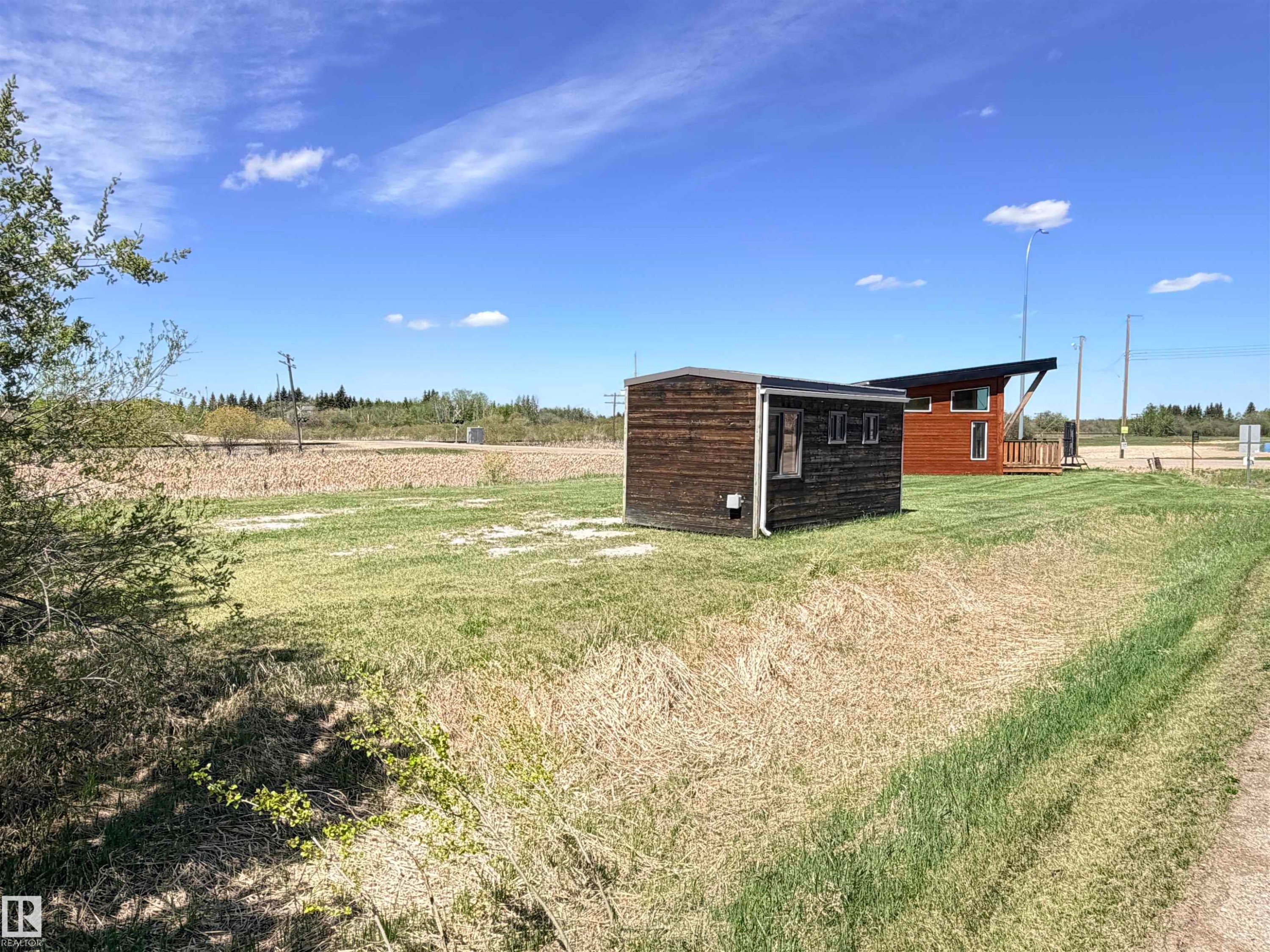 Two distinct structures featuring wood-finish siding and modern architectural elements, set on a broad lot with natural landscaping and open sky - 50 Ave. 52 St., Rural Westlock County, AB
