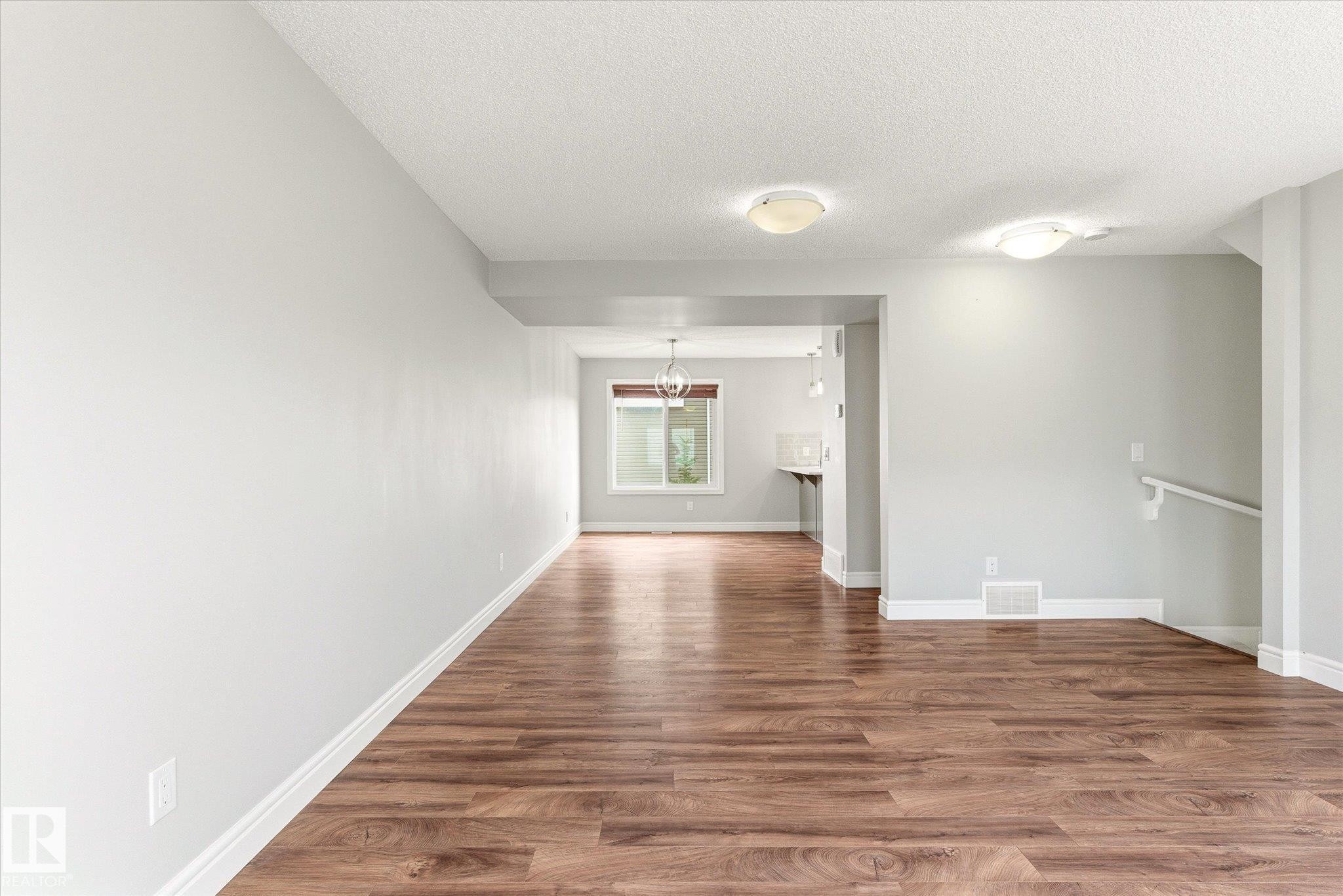 Spacious room featuring wood-finish flooring, light grey wall paint, and white baseboards - 47 330 Bulyea Road, Edmonton, AB - Indoor Photo Showing Other Room