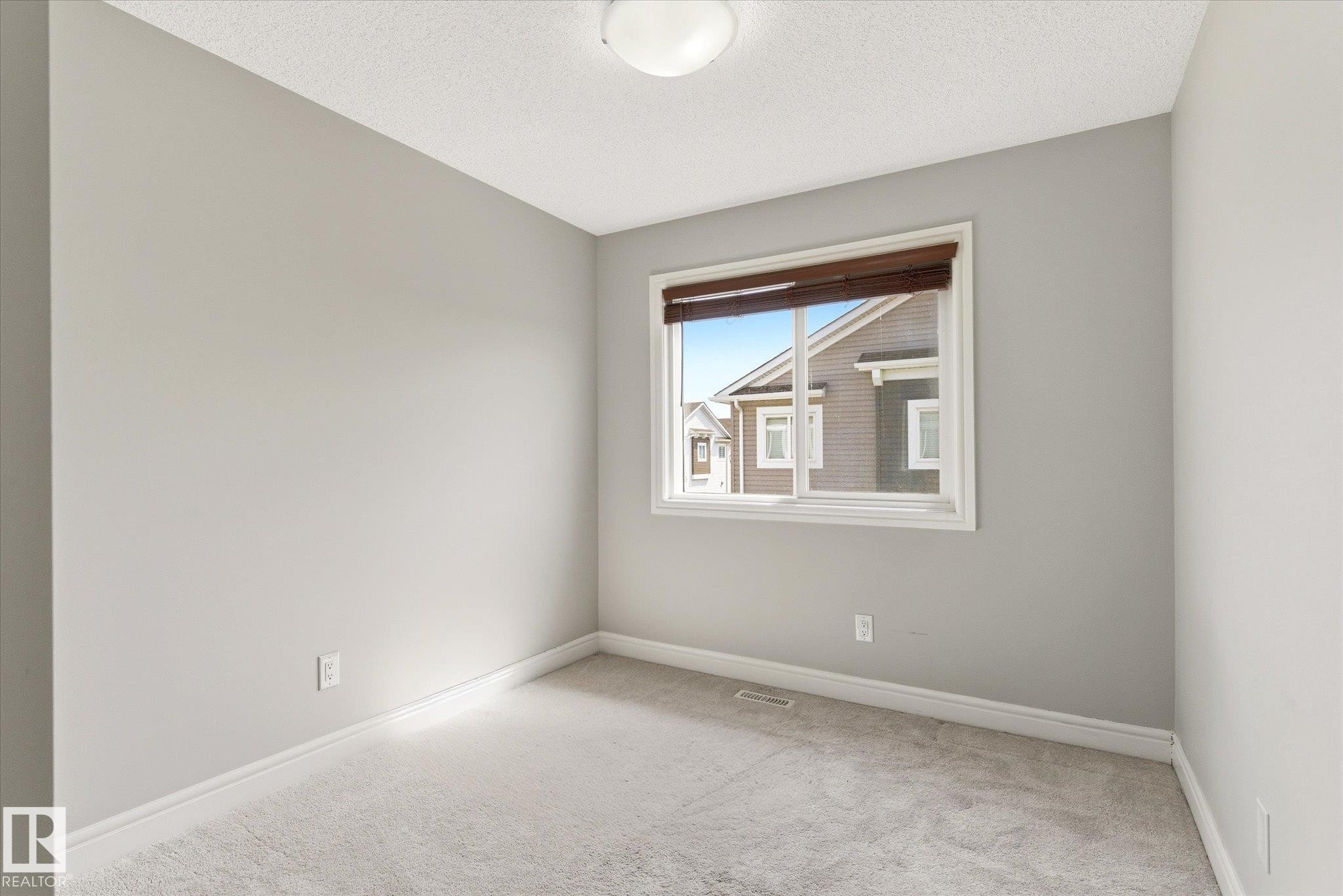 Neutral wall paint, light-colored carpet, and a window with blinds - 47 330 Bulyea Road, Edmonton, AB - Indoor Photo Showing Other Room