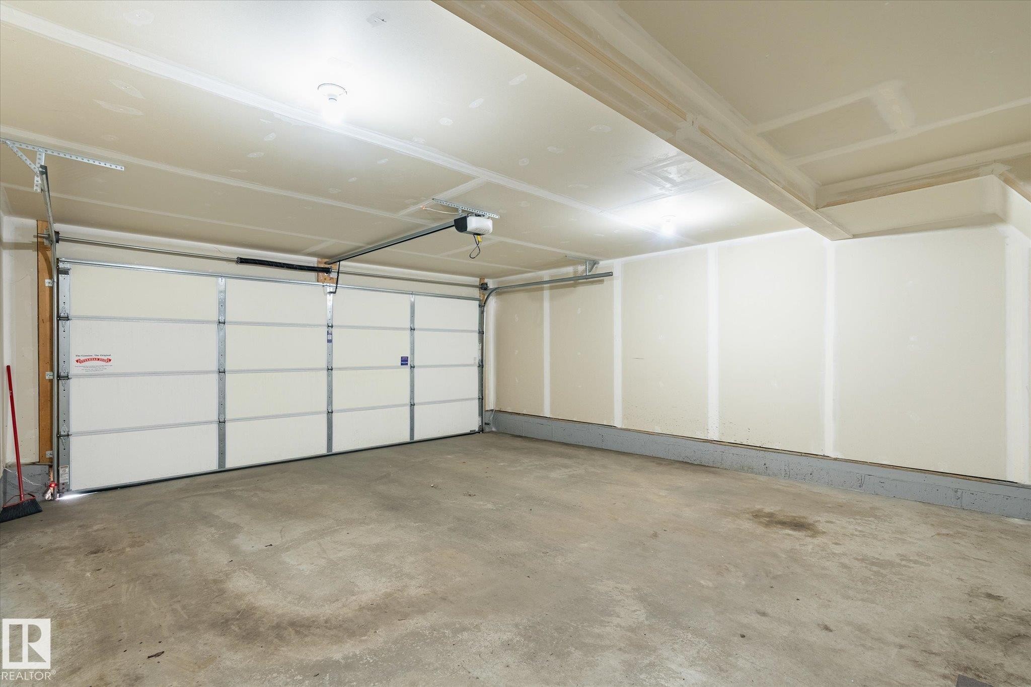 Spacious garage featuring a sectional overhead door with an automatic opener, concrete flooring, and recessed ceiling lighting - 47 330 Bulyea Road, Edmonton, AB - Indoor Photo Showing Garage