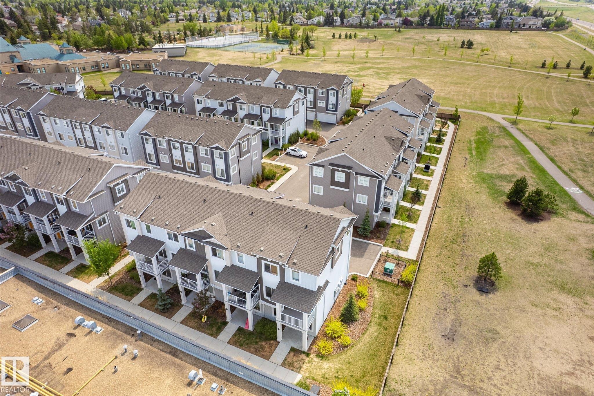 Aerial perspective showcasing a collection of multi-story townhomes with varying exterior finishes and private balconies - 47 330 Bulyea Road, Edmonton, AB - Outdoor With View
