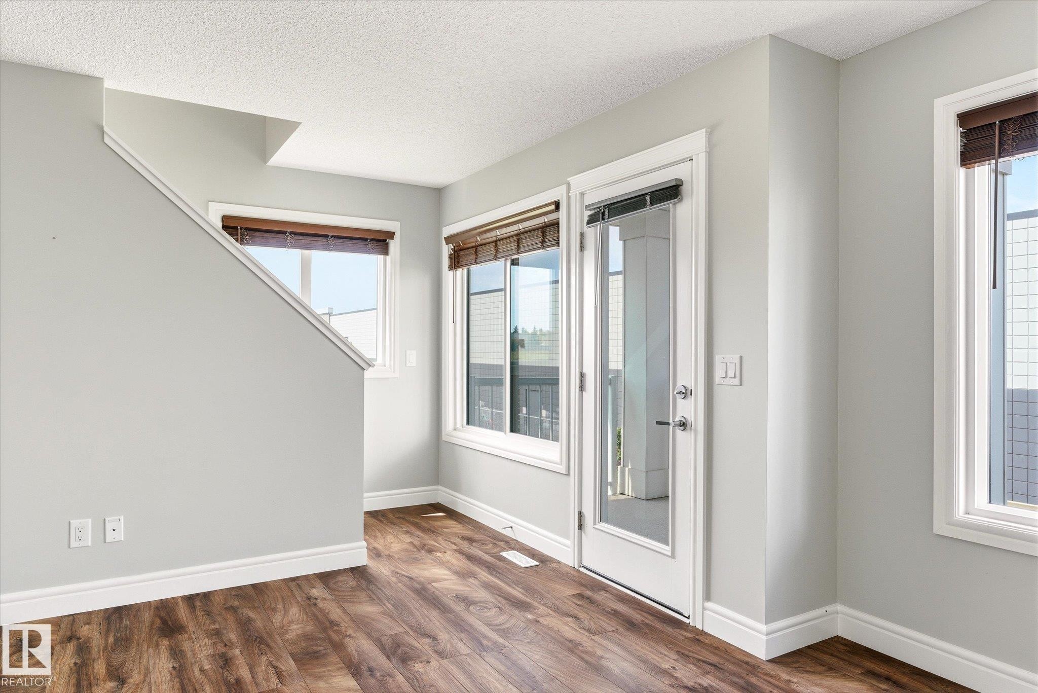 Wood-finish flooring throughout, complemented by light gray walls and white trim - 47 330 Bulyea Road, Edmonton, AB - Indoor Photo Showing Other Room