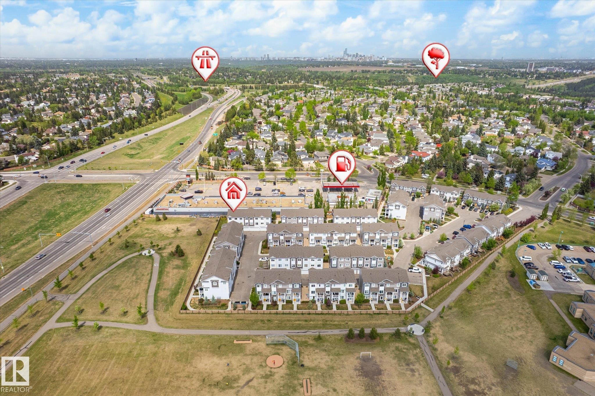 Aerial view showcasing a community of multi-story townhomes with light-colored siding and dark roofs, positioned near a multi-lane roadway - 47 330 Bulyea Road, Edmonton, AB - Outdoor With View