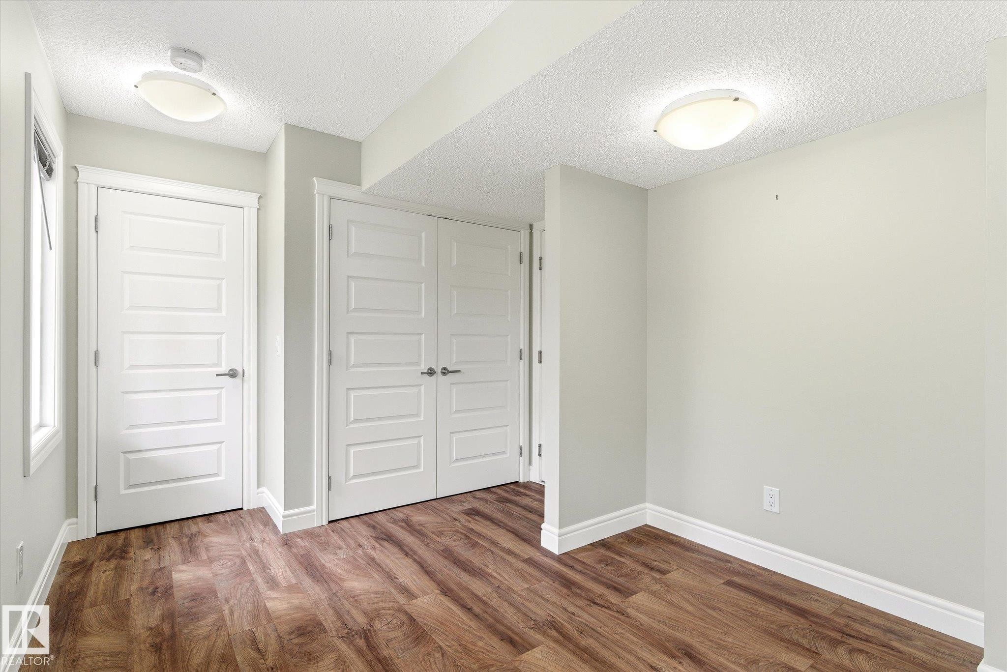 Interior room featuring wood-finish flooring, white baseboards, and light gray walls - 47 330 Bulyea Road, Edmonton, AB - Indoor Photo Showing Other Room