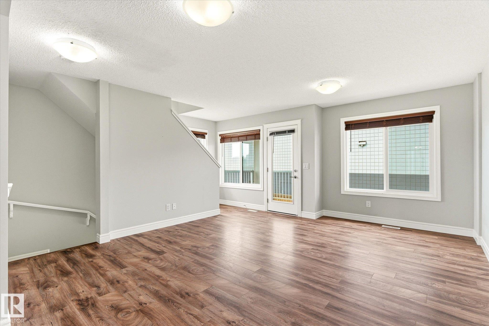 Spacious interior with wood-finish flooring, light grey walls, and white trim - 47 330 Bulyea Road, Edmonton, AB - Indoor Photo Showing Other Room