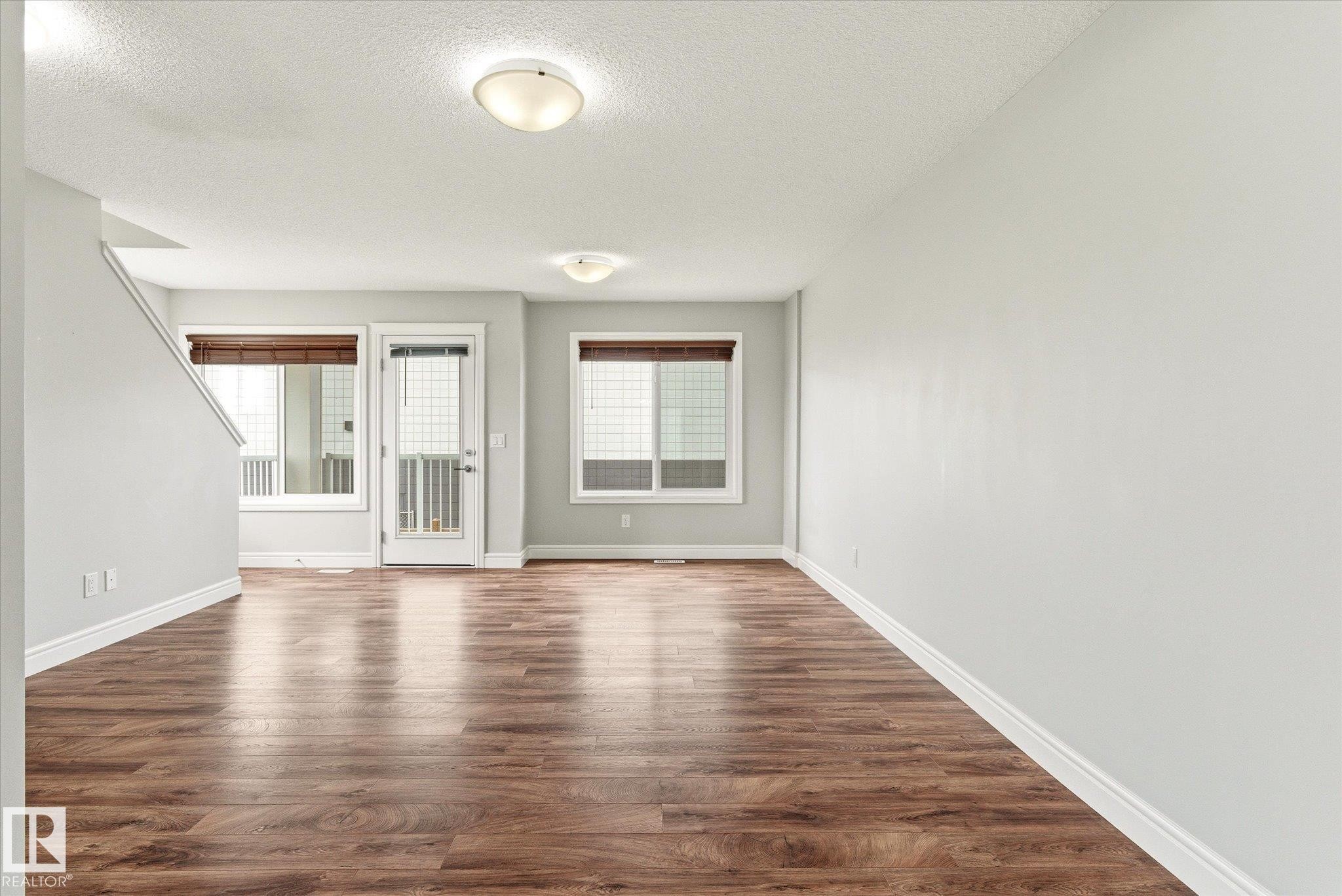 Spacious room featuring wood-finish flooring, light grey walls, white baseboards, and white window trim - 47 330 Bulyea Road, Edmonton, AB - Indoor Photo Showing Other Room