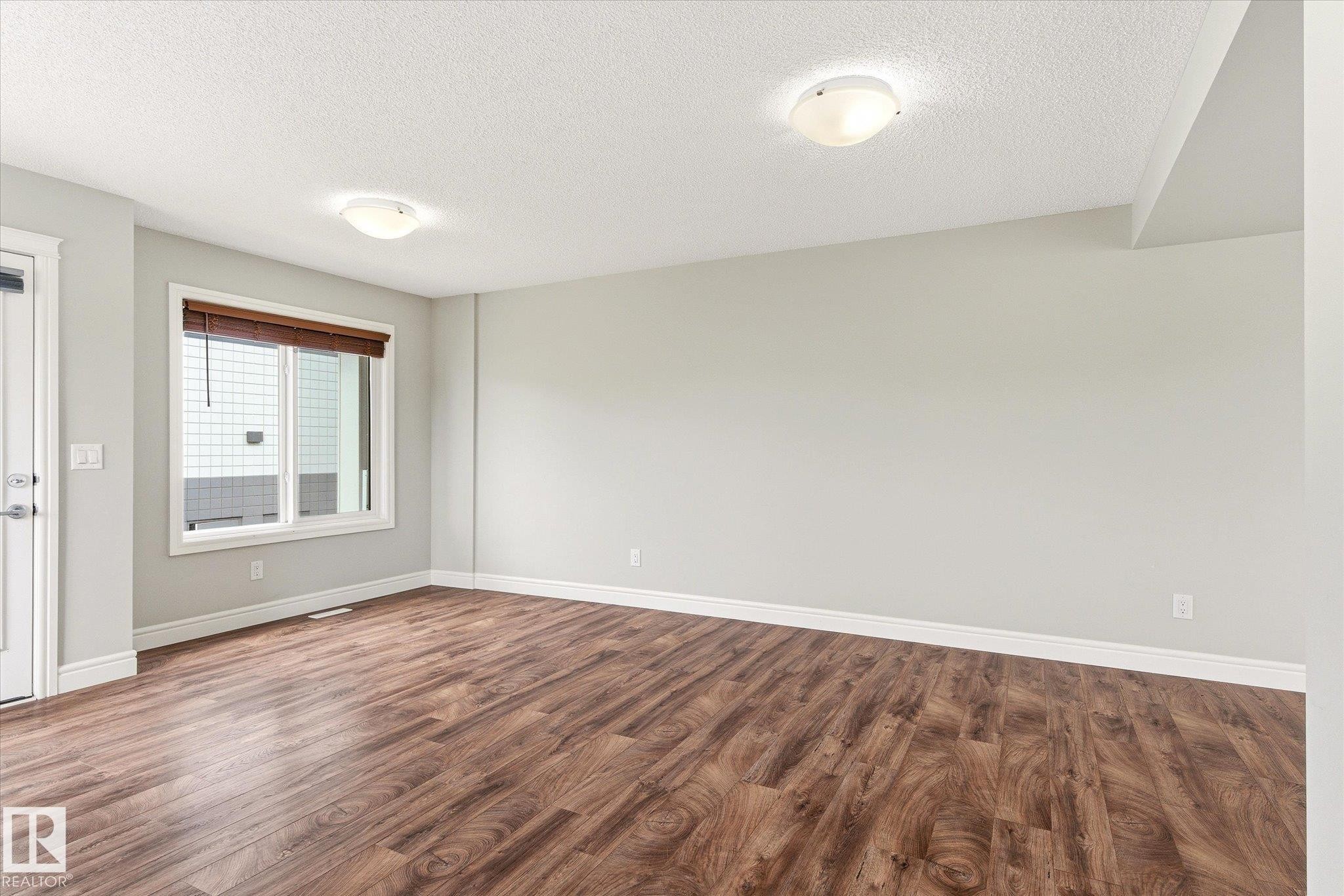 Spacious room featuring wood-finish flooring, light grey walls, and white trim - 47 330 Bulyea Road, Edmonton, AB - Indoor Photo Showing Other Room