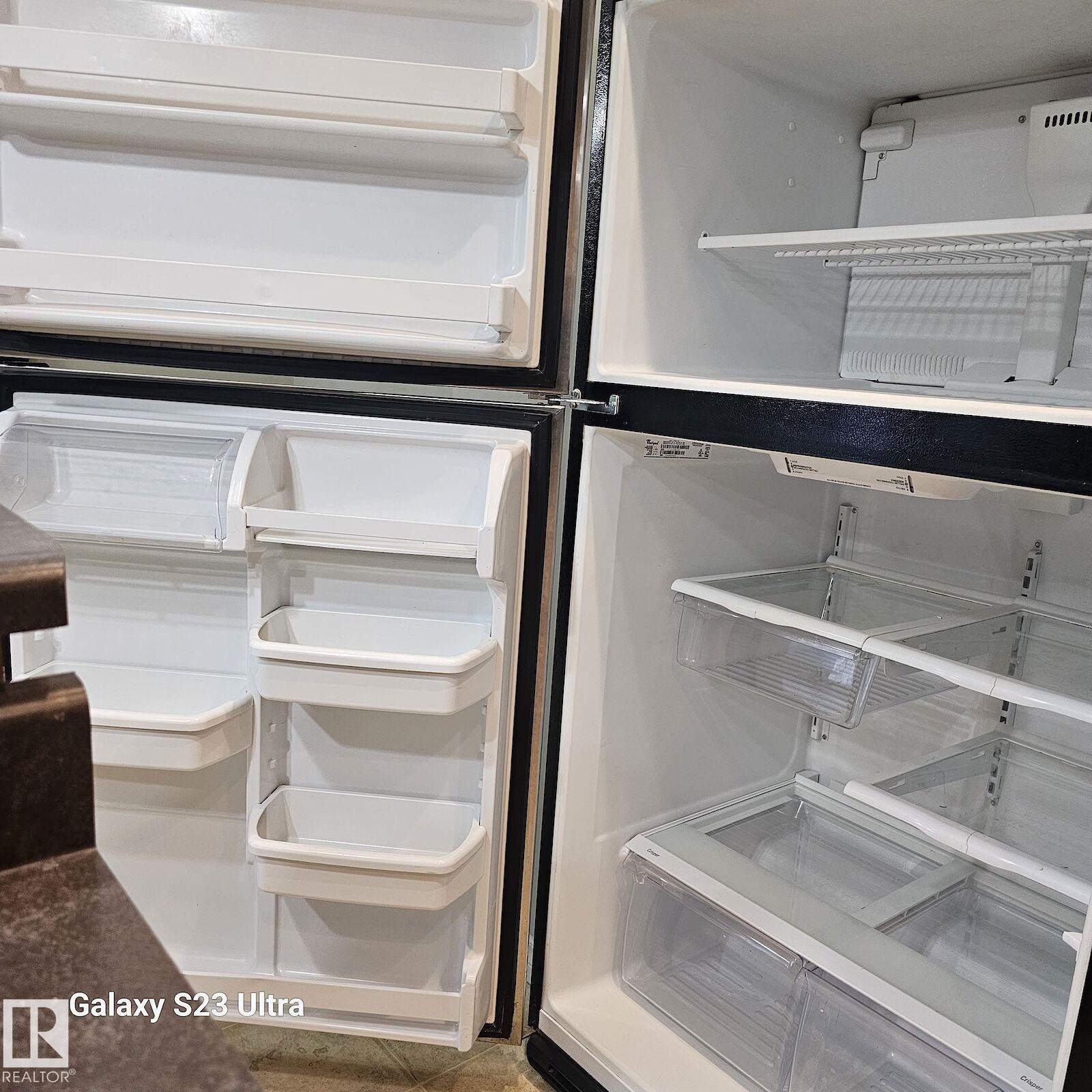 Top-freezer refrigerator featuring multiple door bins, adjustable shelving, clear crisper drawers, and a white interior finish - 99 13825 155 Avenue, Edmonton, AB