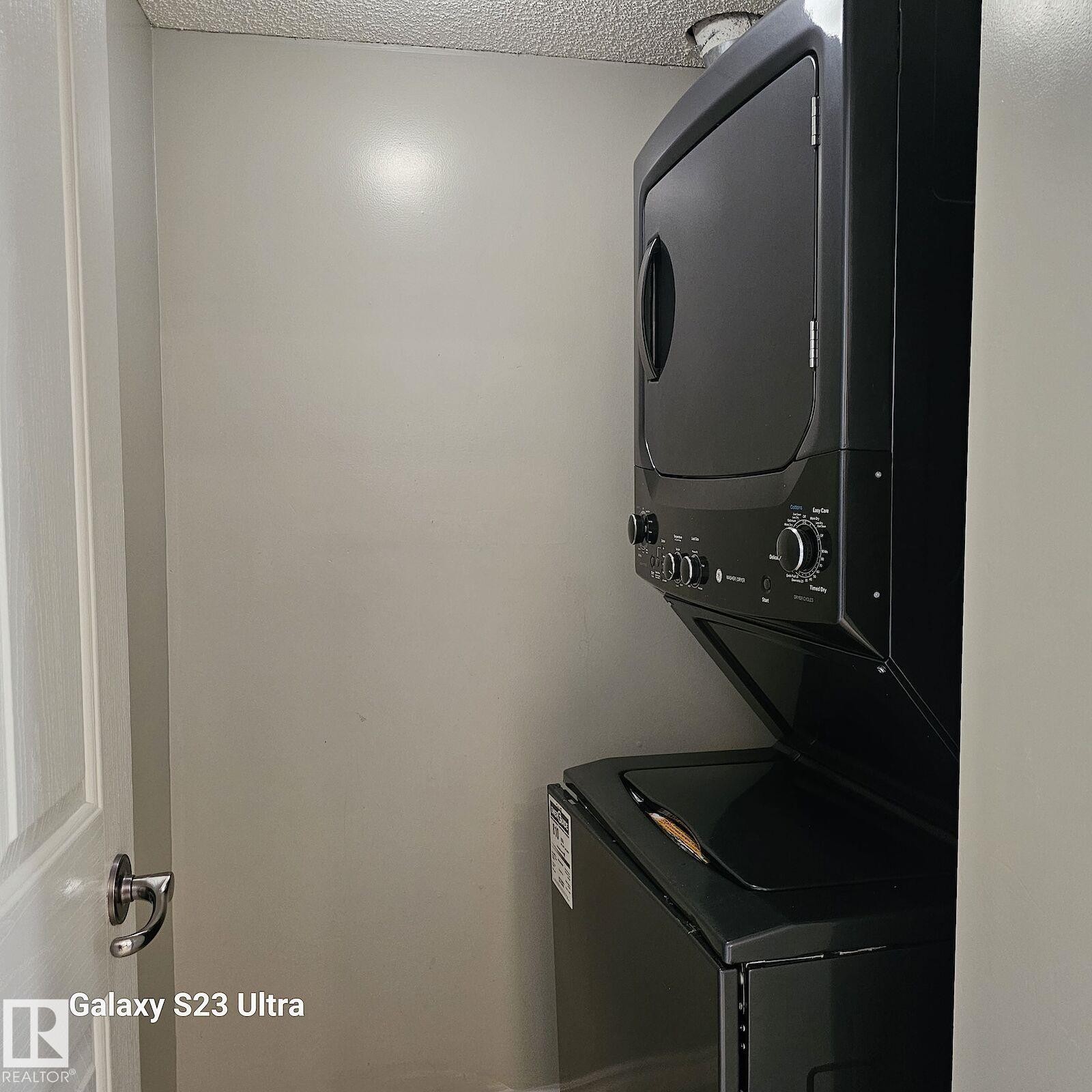 Dedicated laundry area featuring a stacked black washer and dryer unit - 99 13825 155 Avenue, Edmonton, AB