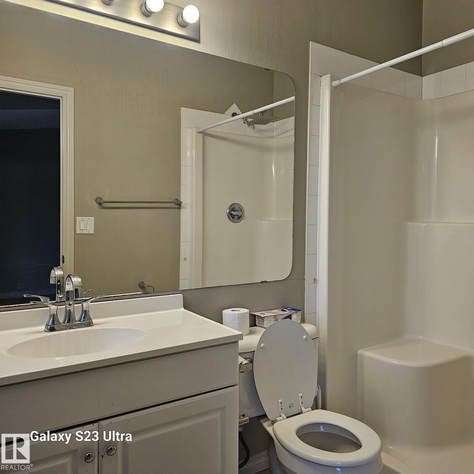 Bathroom featuring a white vanity with an integrated sink, chrome faucet, and overhead bar lighting - 99 13825 155 Avenue, Edmonton, AB