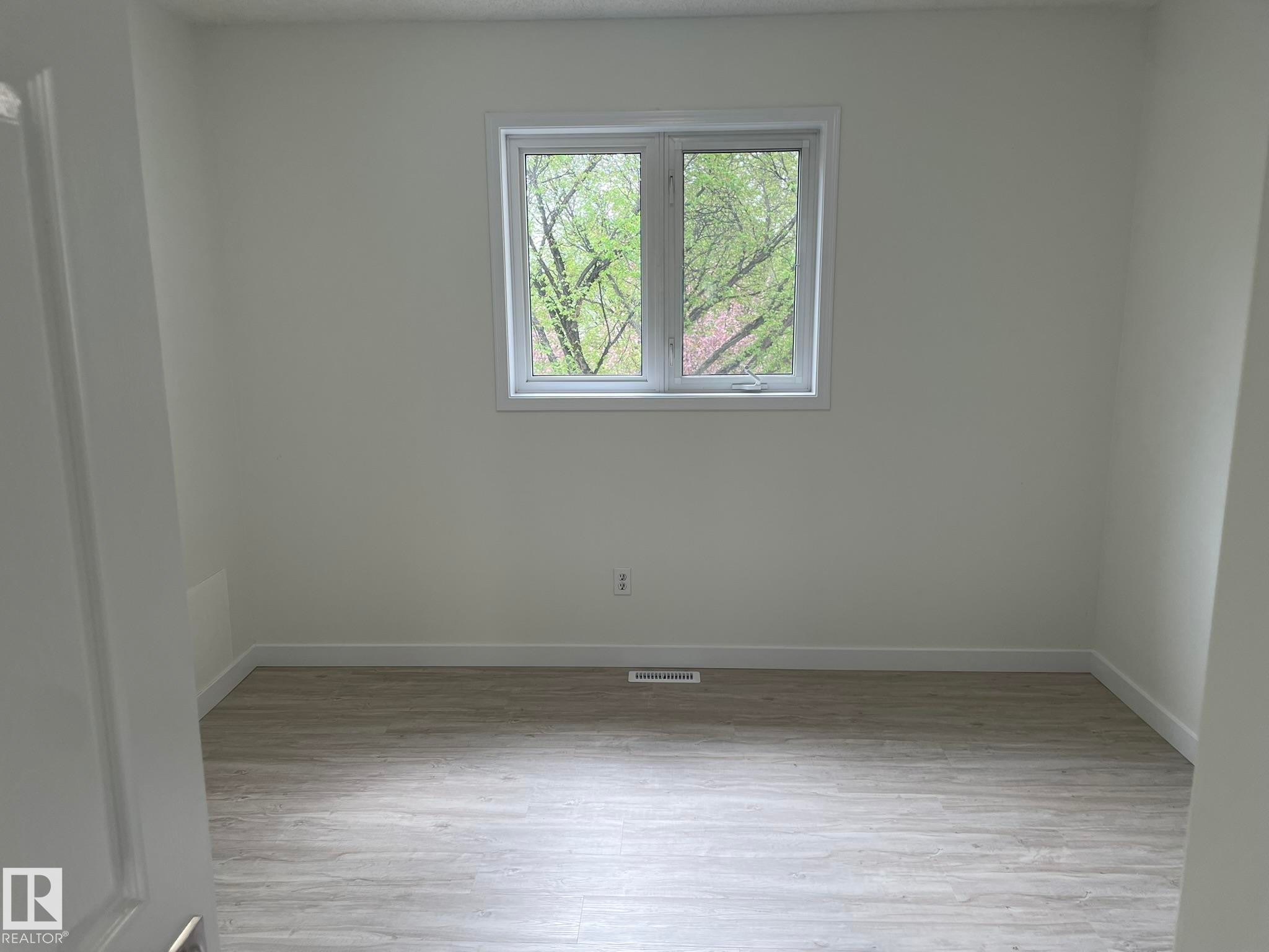 Room featuring light wood-finish flooring, white walls, and a casement window with white trim - 2 1295 Carter Crest Road, Edmonton, AB - Indoor Photo Showing Other Room