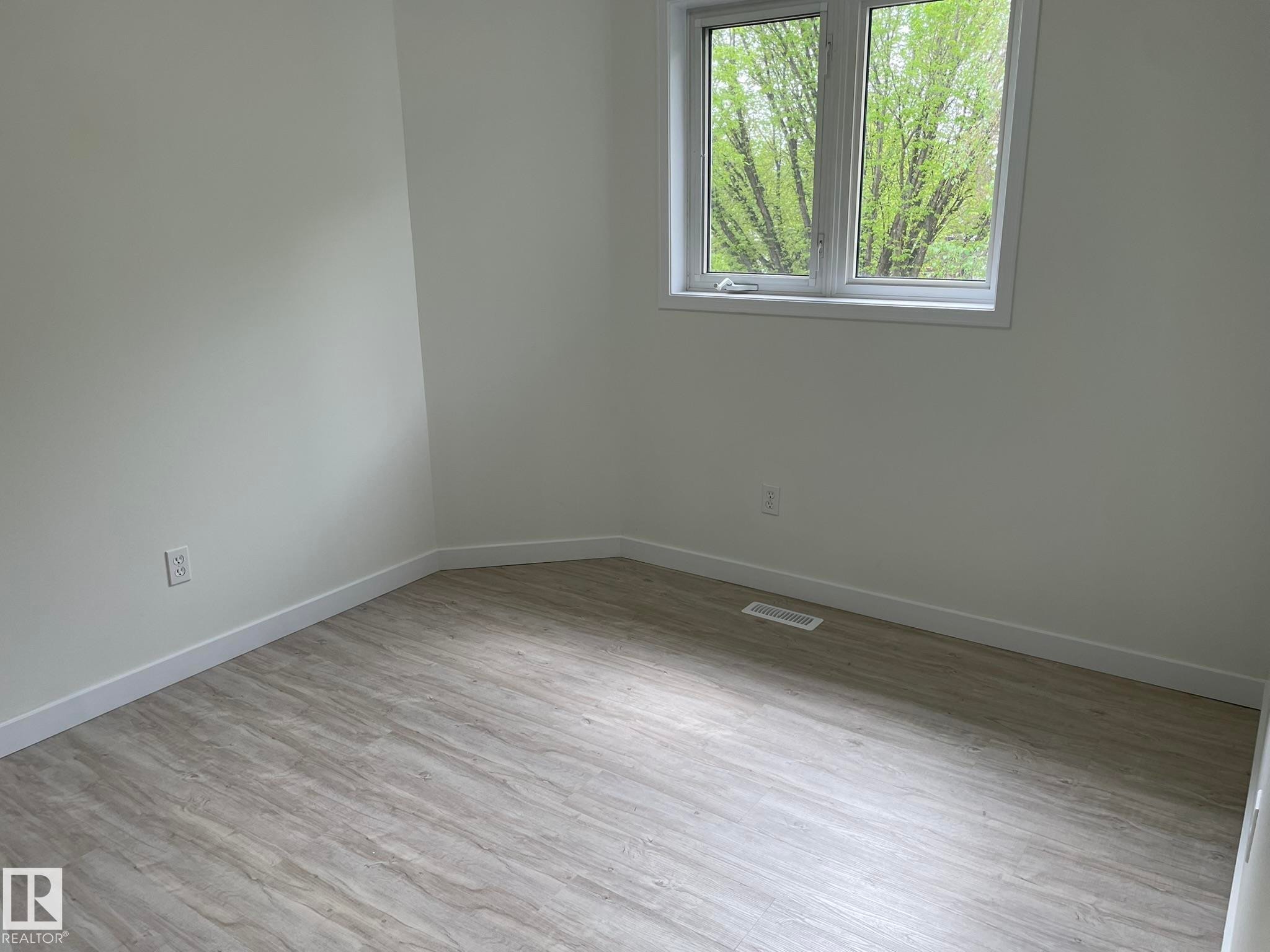 Bright room featuring wood-finish flooring, crisp white walls, and a large window - 2 1295 Carter Crest Road, Edmonton, AB - Indoor Photo Showing Other Room