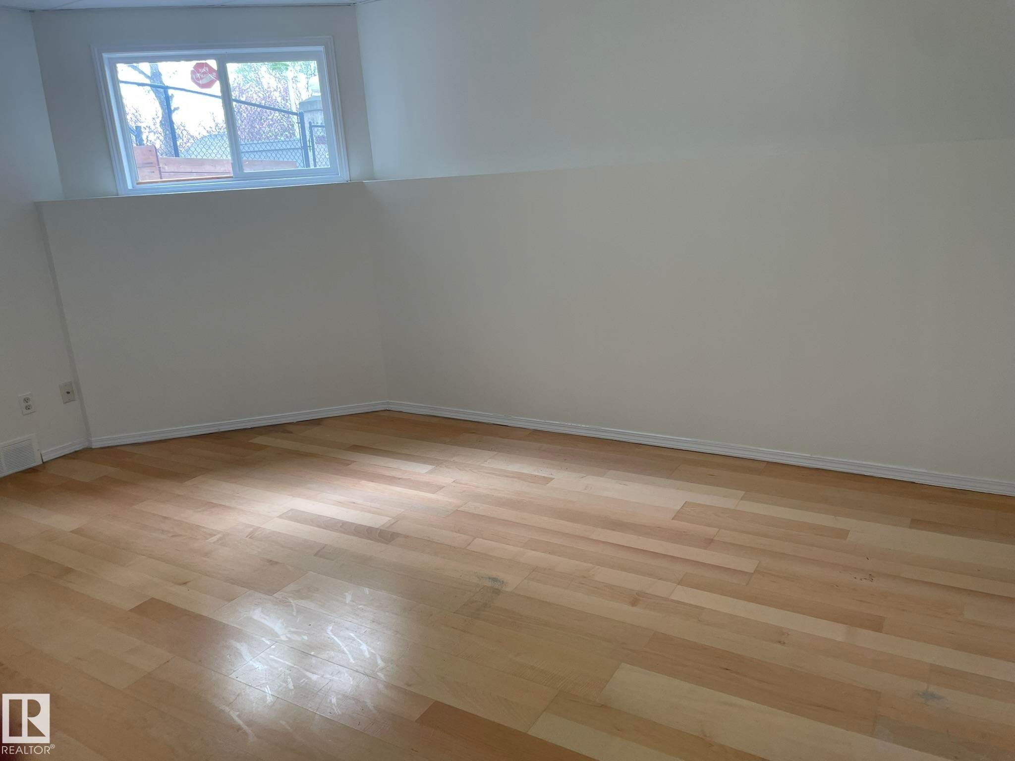 Light wood-finish flooring with white baseboards and a window with white trim - 2 1295 Carter Crest Road, Edmonton, AB - Indoor Photo Showing Other Room