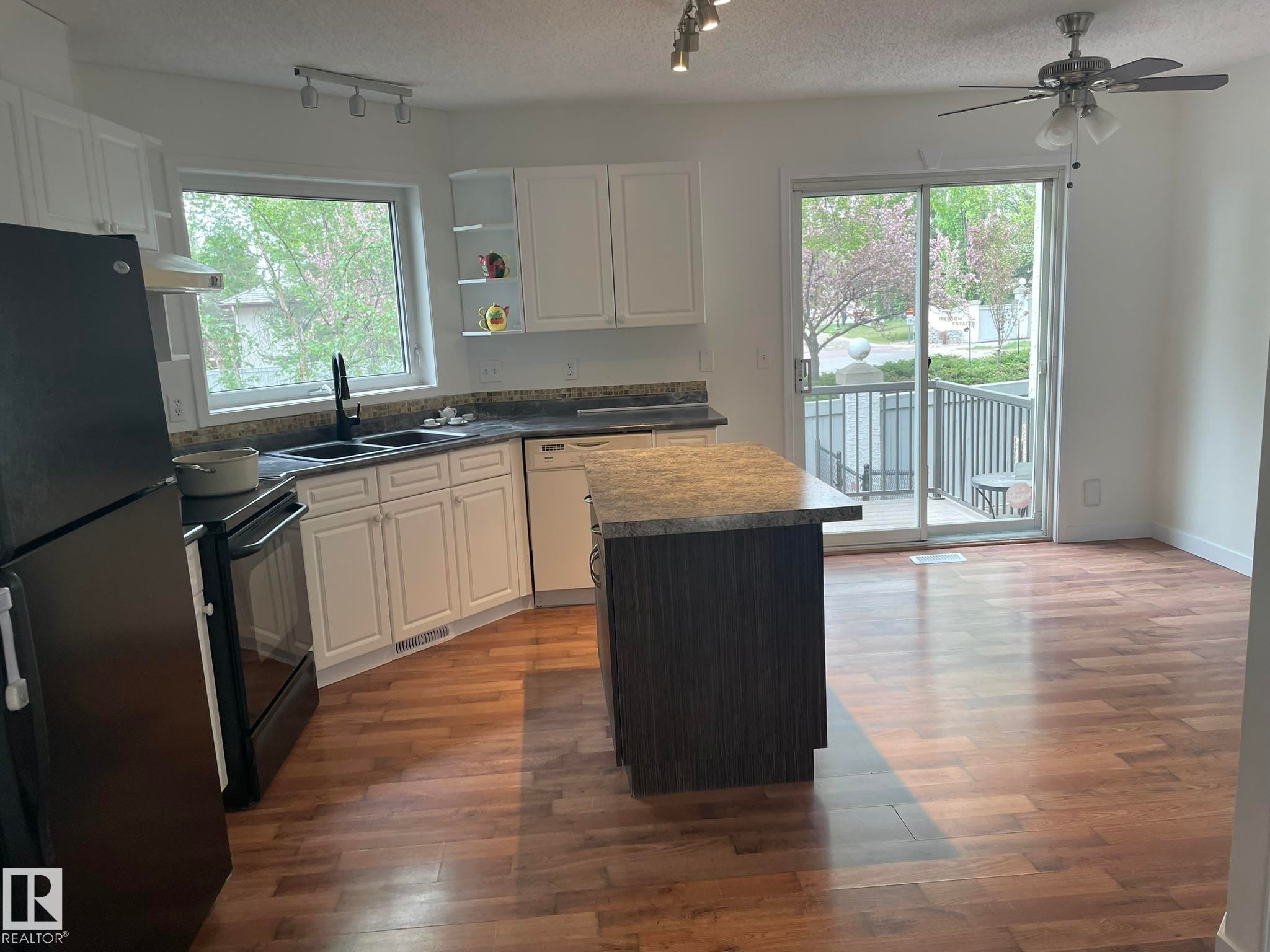 Open-concept kitchen featuring white cabinetry, a central island with a granite-style countertop, and wood-finish flooring - 2 1295 Carter Crest Road, Edmonton, AB - Indoor Photo Showing Kitchen With Double Sink