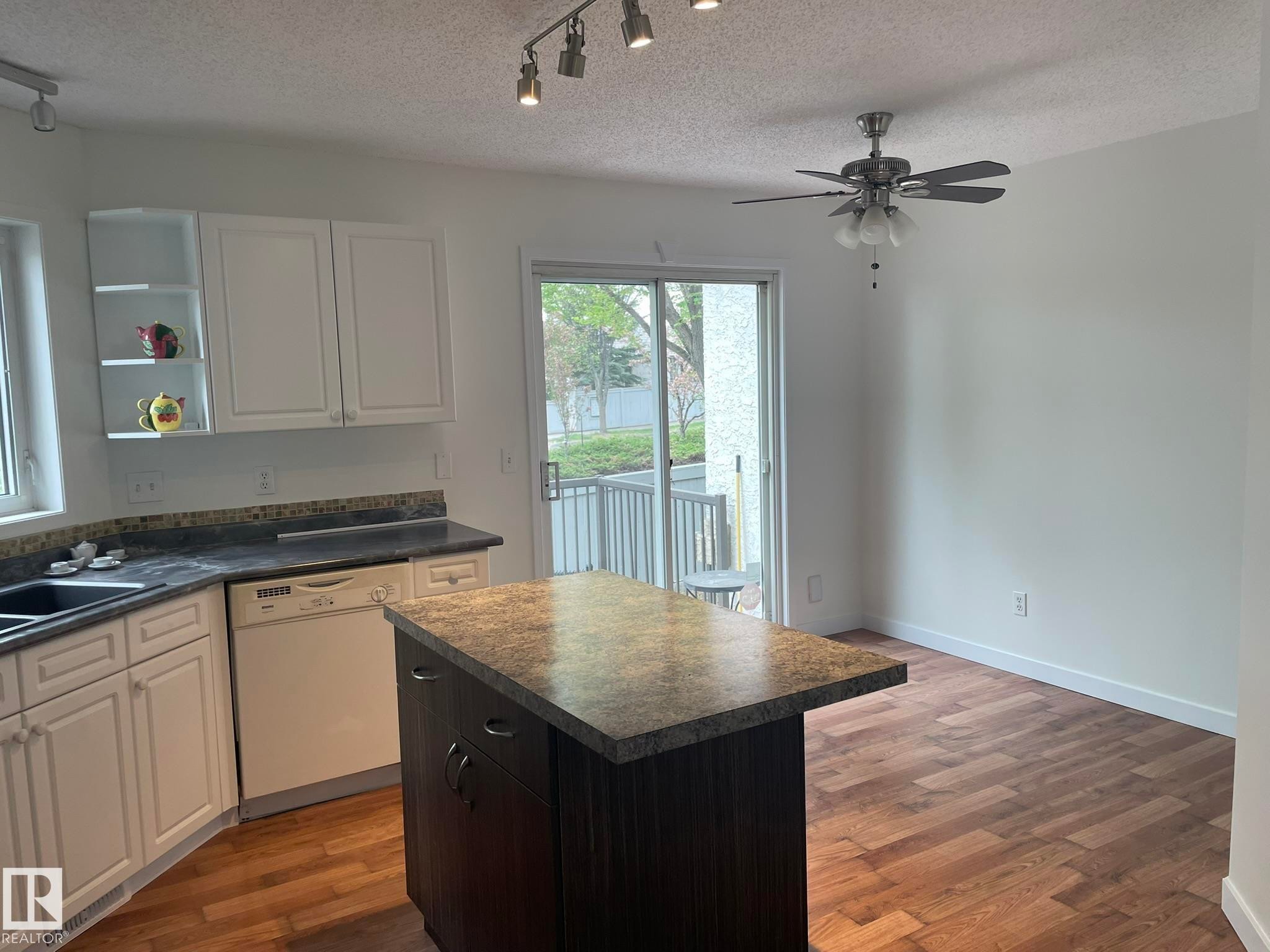 Kitchen featuring white cabinetry, dark countertops, and a central island with an extended counter - 2 1295 Carter Crest Road, Edmonton, AB - Indoor Photo Showing Kitchen