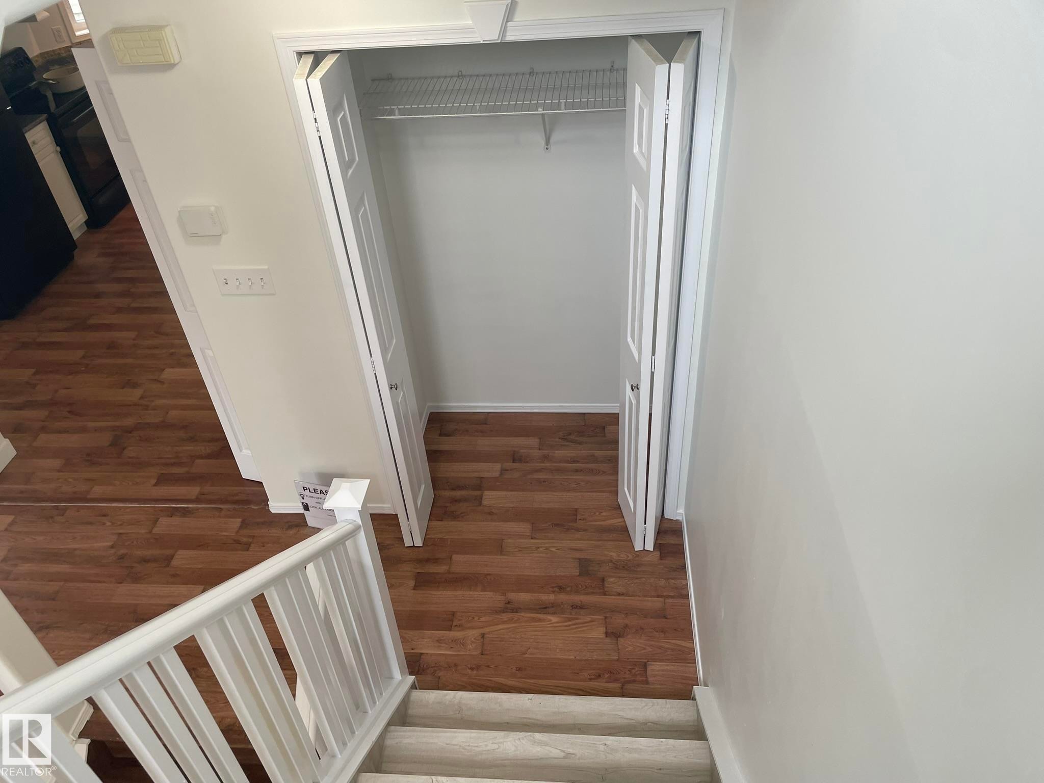 Open closet with bifold paneled doors, wire shelving, and wood-finish flooring - 2 1295 Carter Crest Road, Edmonton, AB - Indoor Photo Showing Other Room
