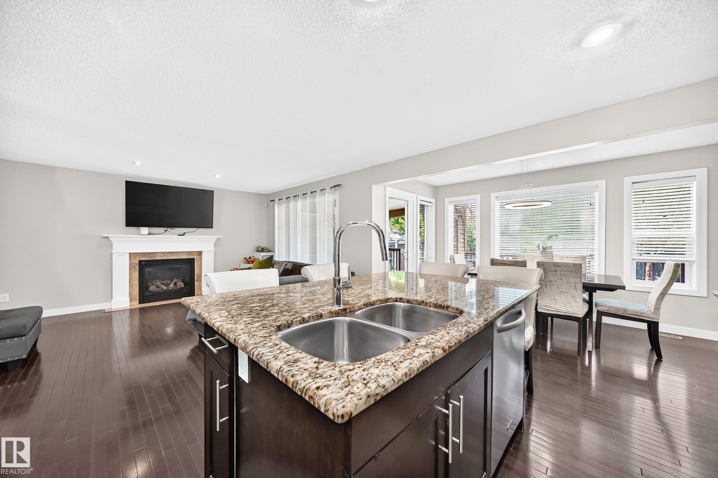 Kitchen island with dual stainless steel sinks and a stone-finish countertop - 3433 Goodridge Link Link, Edmonton, AB