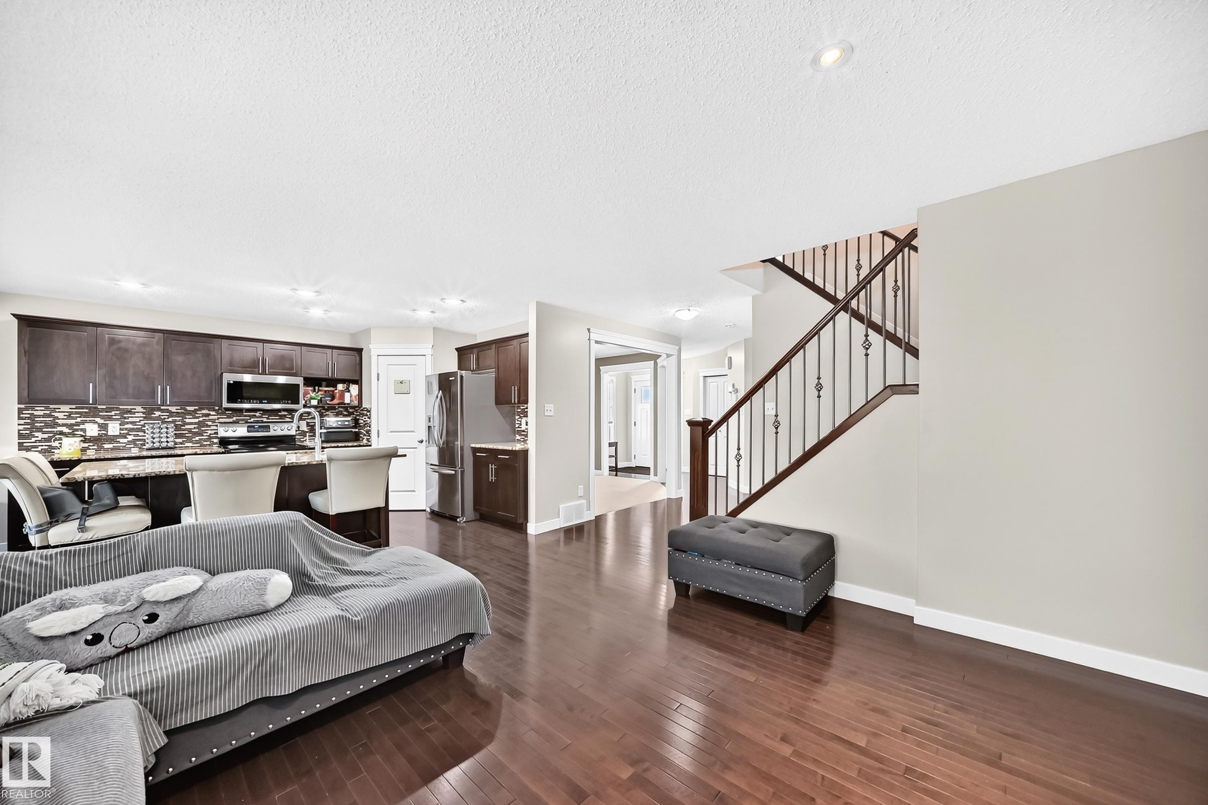 Open-concept living space featuring wood-finish flooring and recessed lighting - 3433 Goodridge Link Link, Edmonton, AB