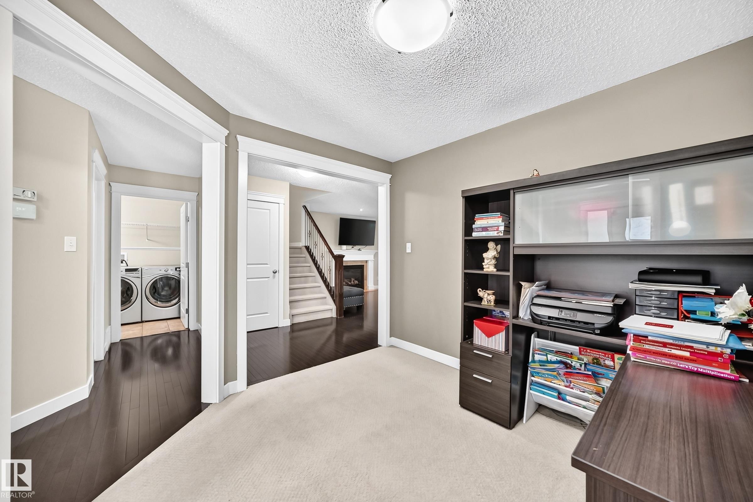 Carpeted room with a built-in dark wood-finish desk and shelving unit - 3433 Goodridge Link Link, Edmonton, AB