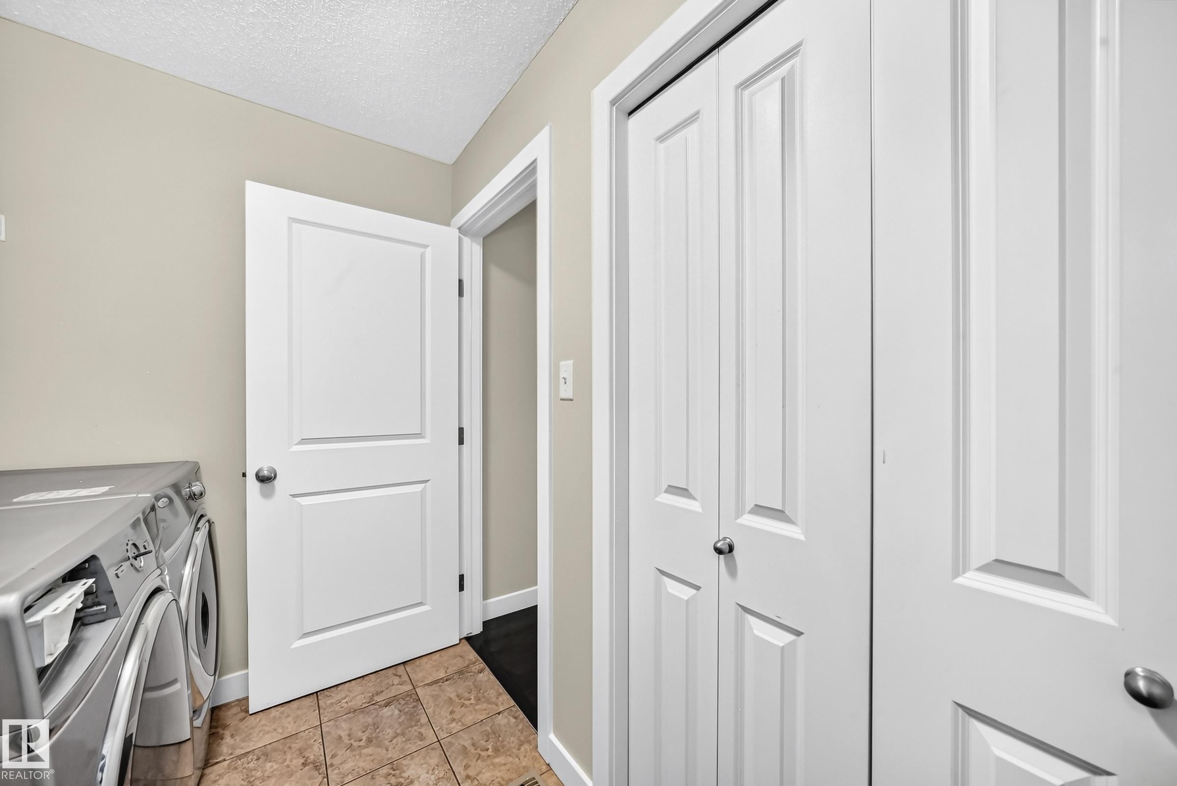 Utility area featuring light beige walls, textured ceiling, and tiled flooring - 3433 Goodridge Link Link, Edmonton, AB