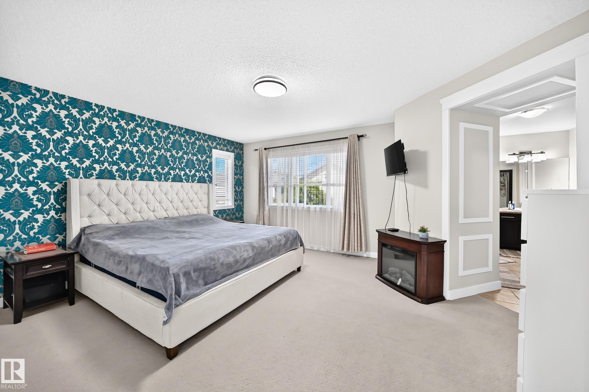 Spacious room featuring a prominent accent wall with a teal damask pattern - 3433 Goodridge Link Link, Edmonton, AB