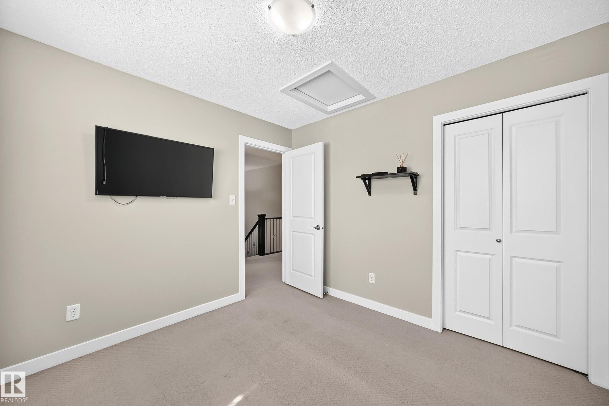 Carpeted room featuring light gray wall paint, white baseboards, and a white six-panel bifold closet door - 3433 Goodridge Link Link, Edmonton, AB