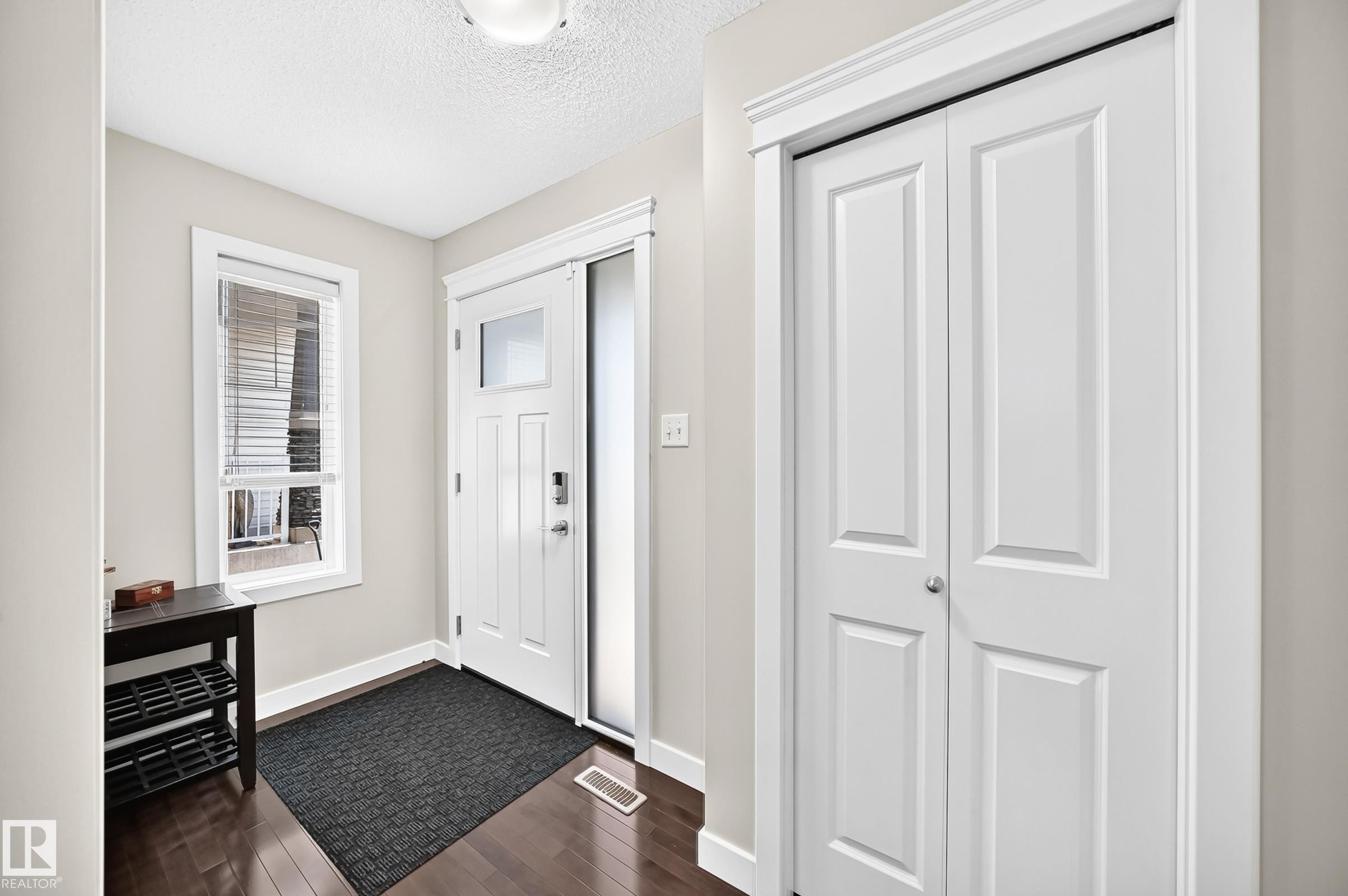 Entryway featuring wood-finish flooring and a white paneled door with glass inserts - 3433 Goodridge Link Link, Edmonton, AB