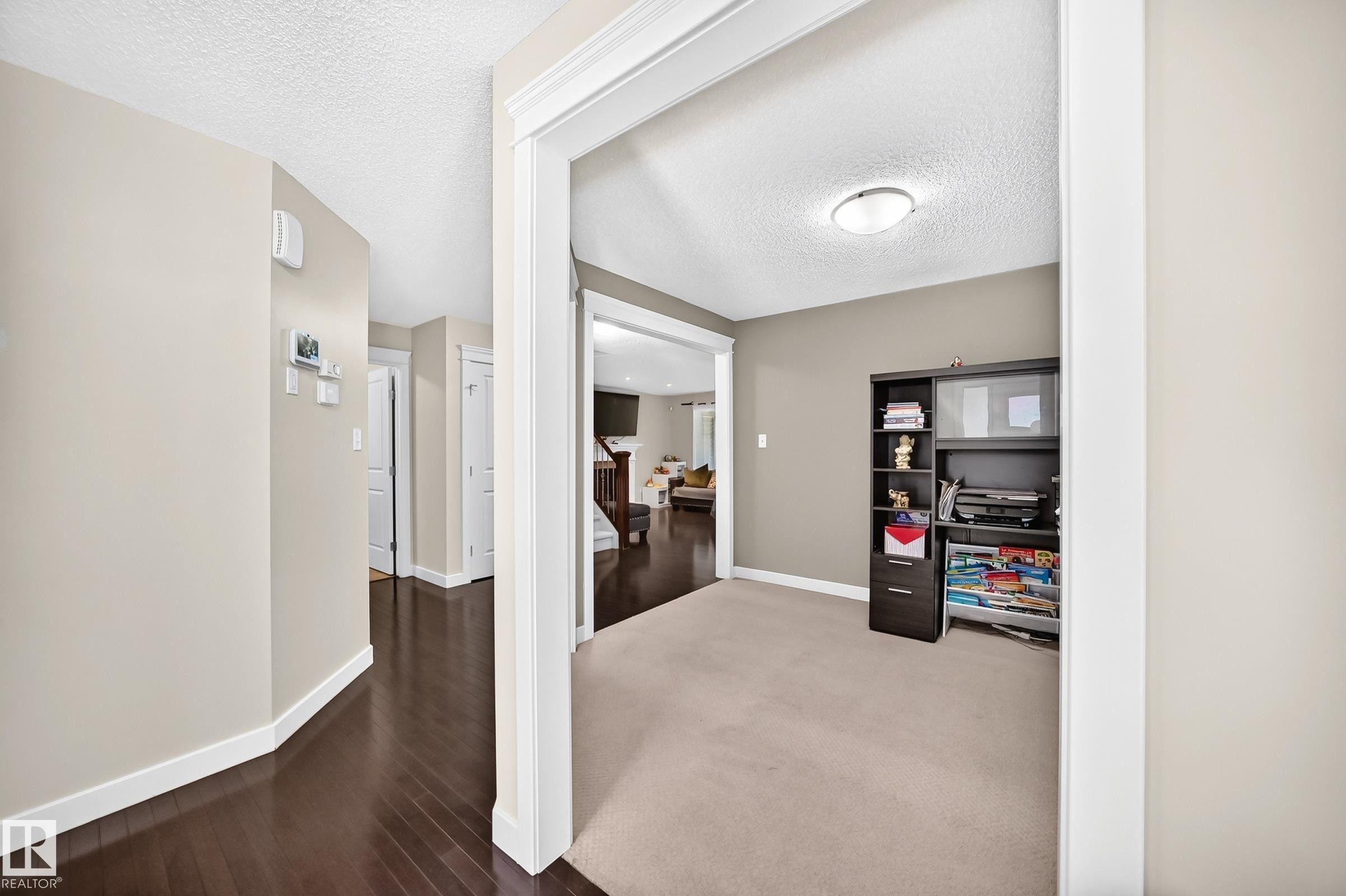 Entryway featuring dark wood-finish flooring, light neutral wall tones, and white trim - 3433 Goodridge Link Link, Edmonton, AB