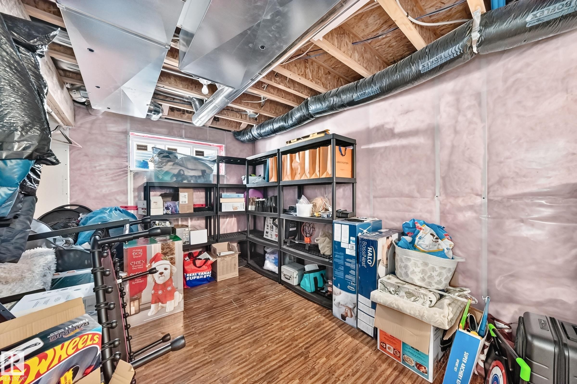 Unfinished basement featuring exposed ceiling joists, visible ductwork, a small window, and wood-finish flooring - 3433 Goodridge Link Link, Edmonton, AB