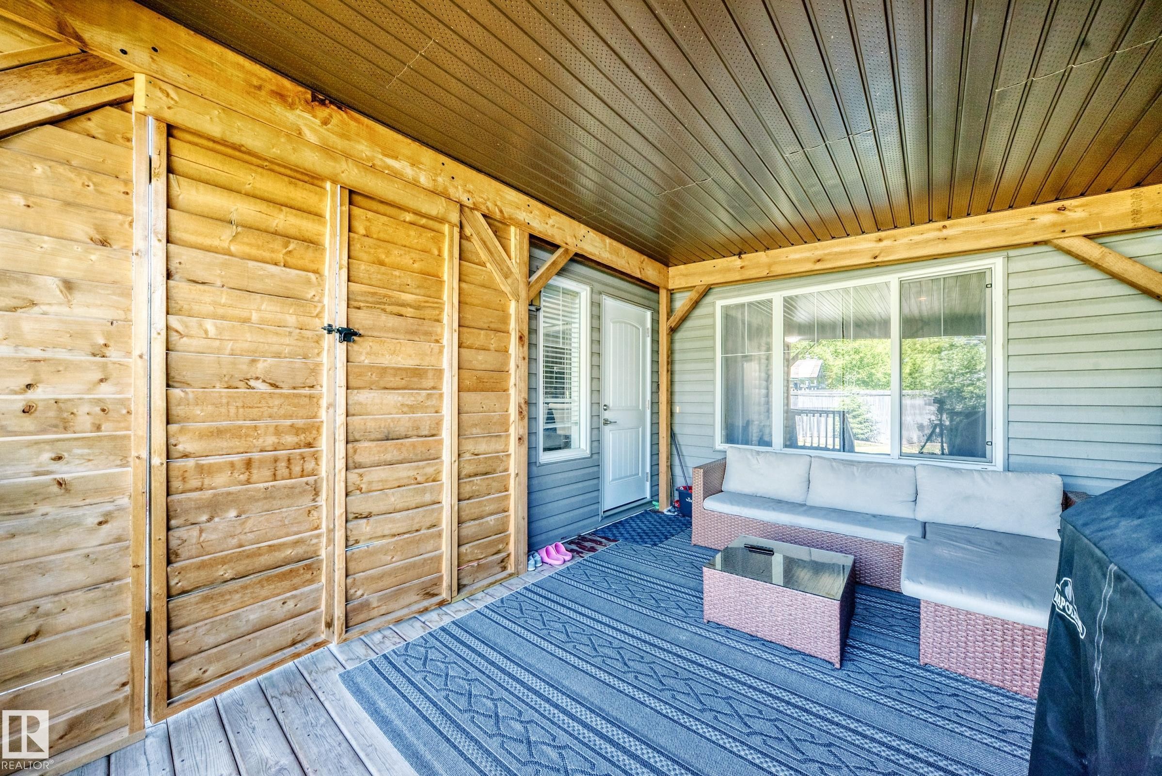 Covered patio with a wood-finish plank ceiling and matching wood-finish beam supports - 3433 Goodridge Link Link, Edmonton, AB