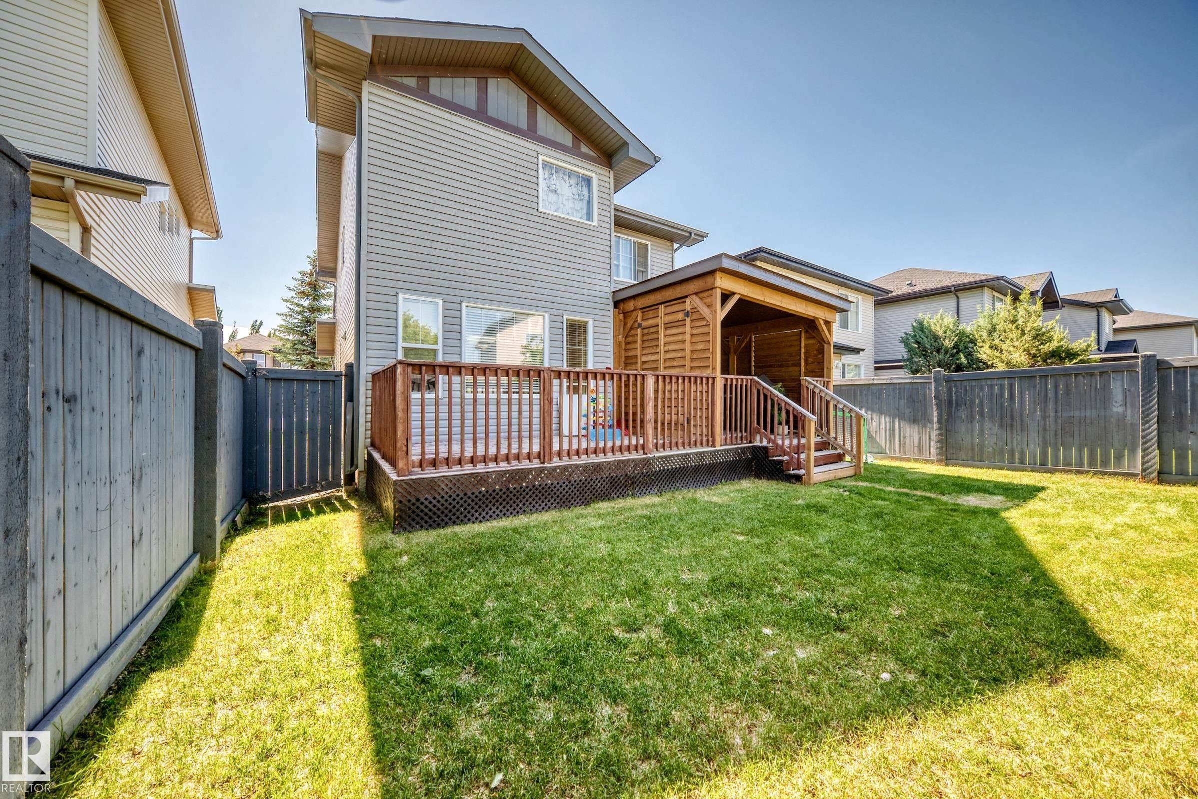 Expansive backyard featuring a lush lawn, a multi-level wood deck, a covered gazebo, and privacy fencing - 3433 Goodridge Link Link, Edmonton, AB