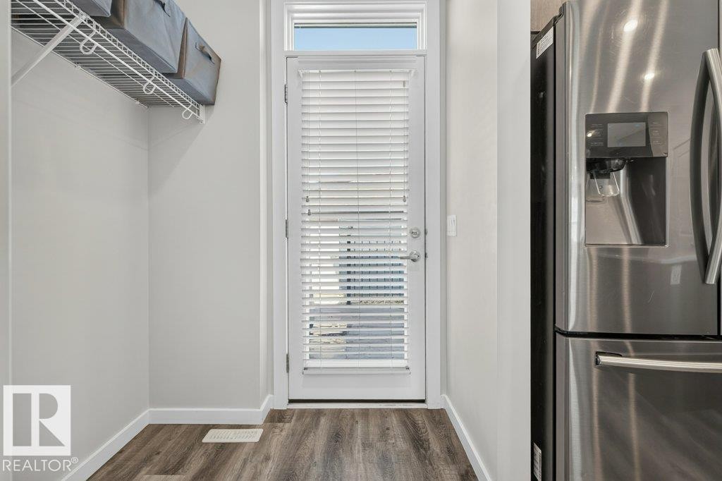 Entryway featuring wood-finish flooring, a full-lite door with integrated blinds, and a transom window - 2116 Maple Road, Edmonton, AB