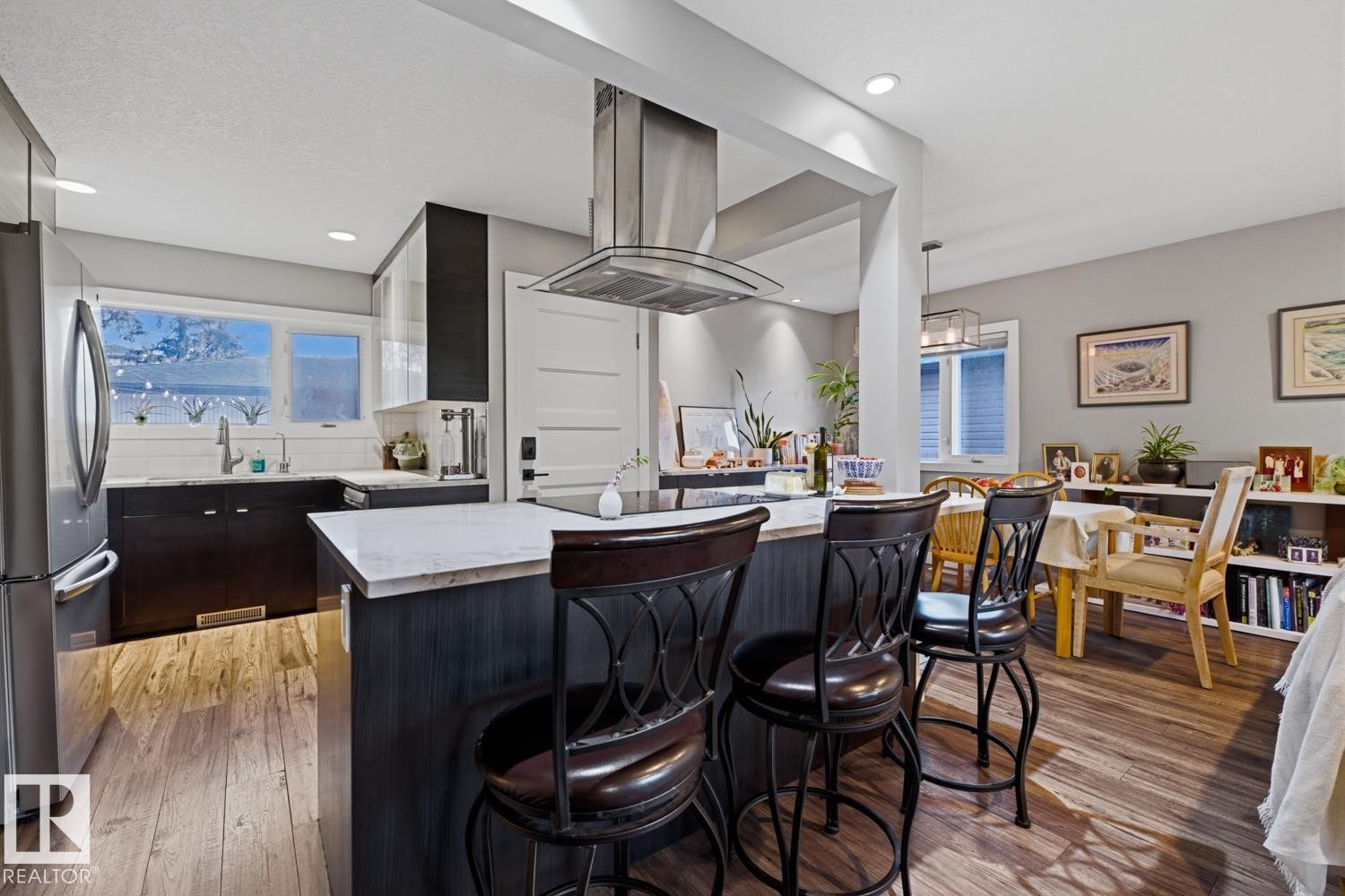 Open-concept kitchen featuring stainless steel appliances and an island with room for seating - 10328 73 Street, Edmonton, AB