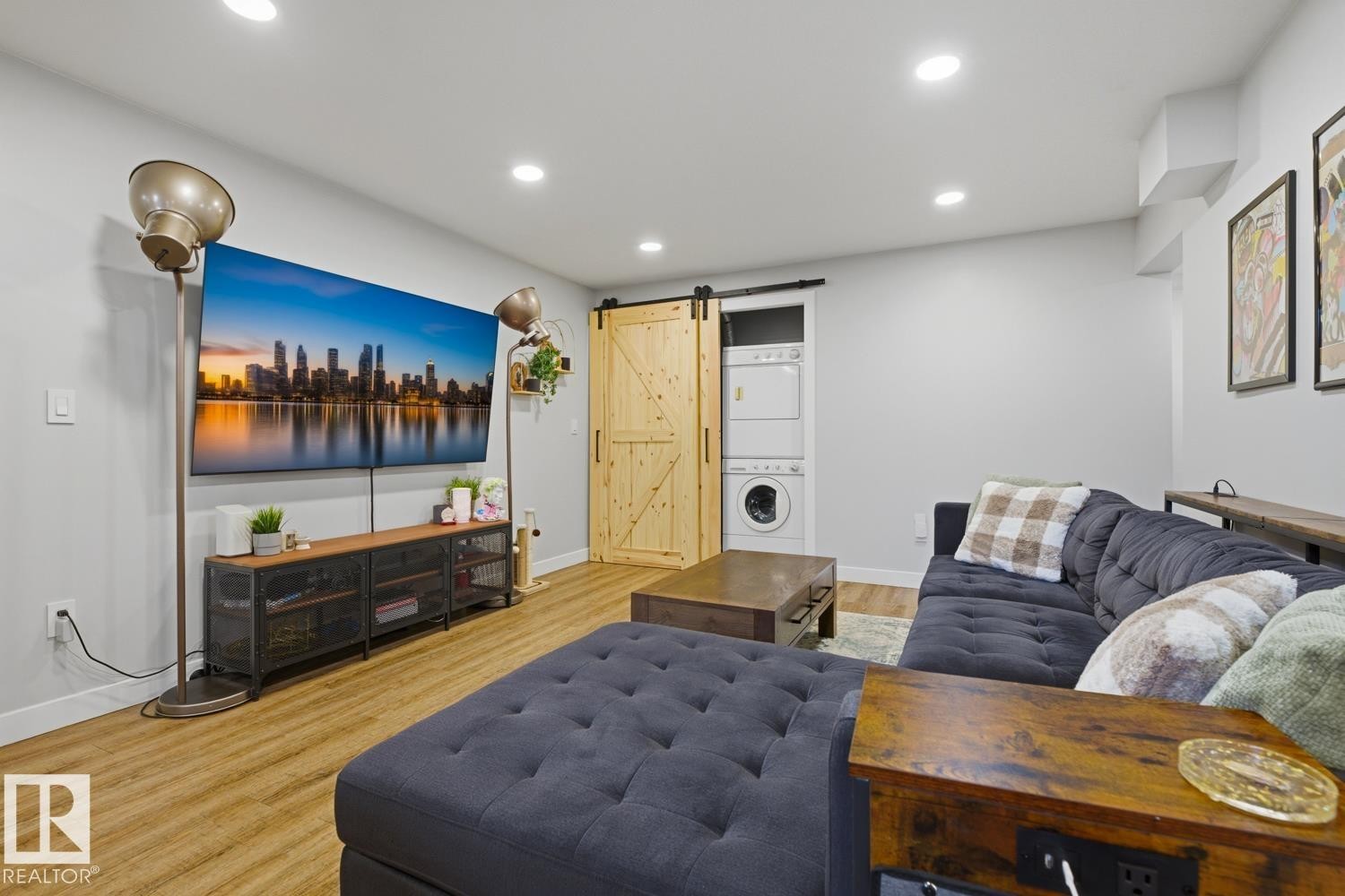Well lit, open-concept living space with recessed lighting and barn doors for in-suite stacking laundry as well as primary basement bedroom - 10328 73 Street, Edmonton, AB